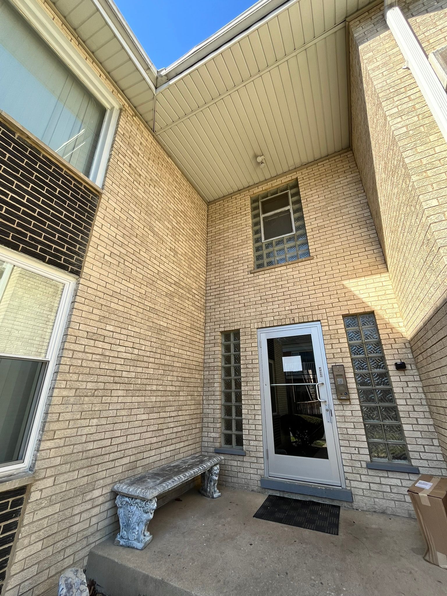 a brick building with a white door and a bench in front of it .
