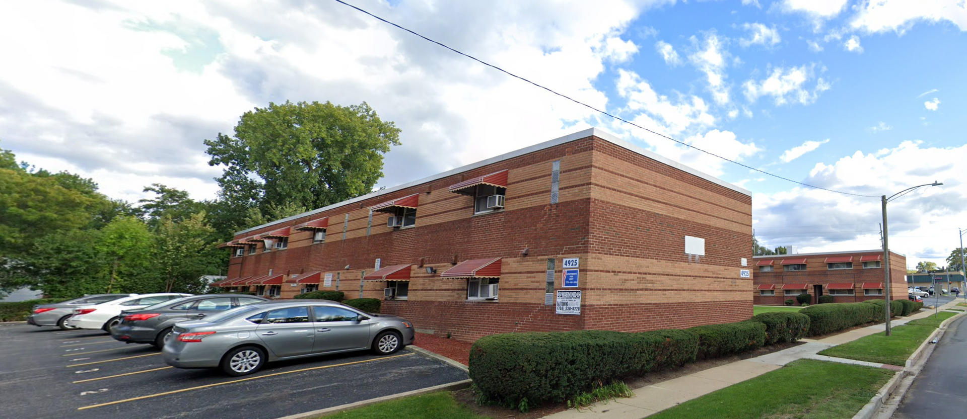 a row of cars are parked in front of a large brick building .