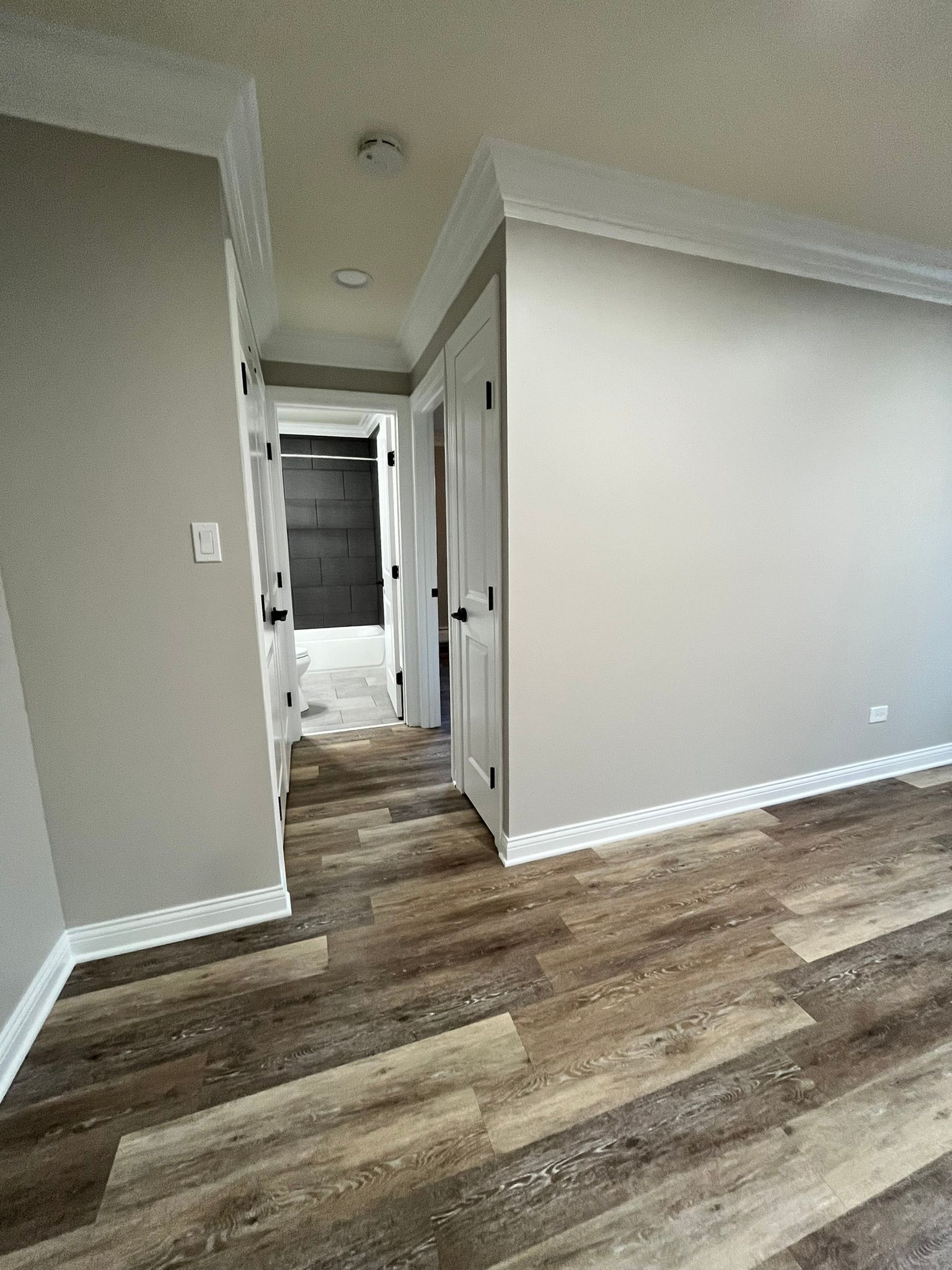 A hallway in a house with hardwood floors and gray walls.