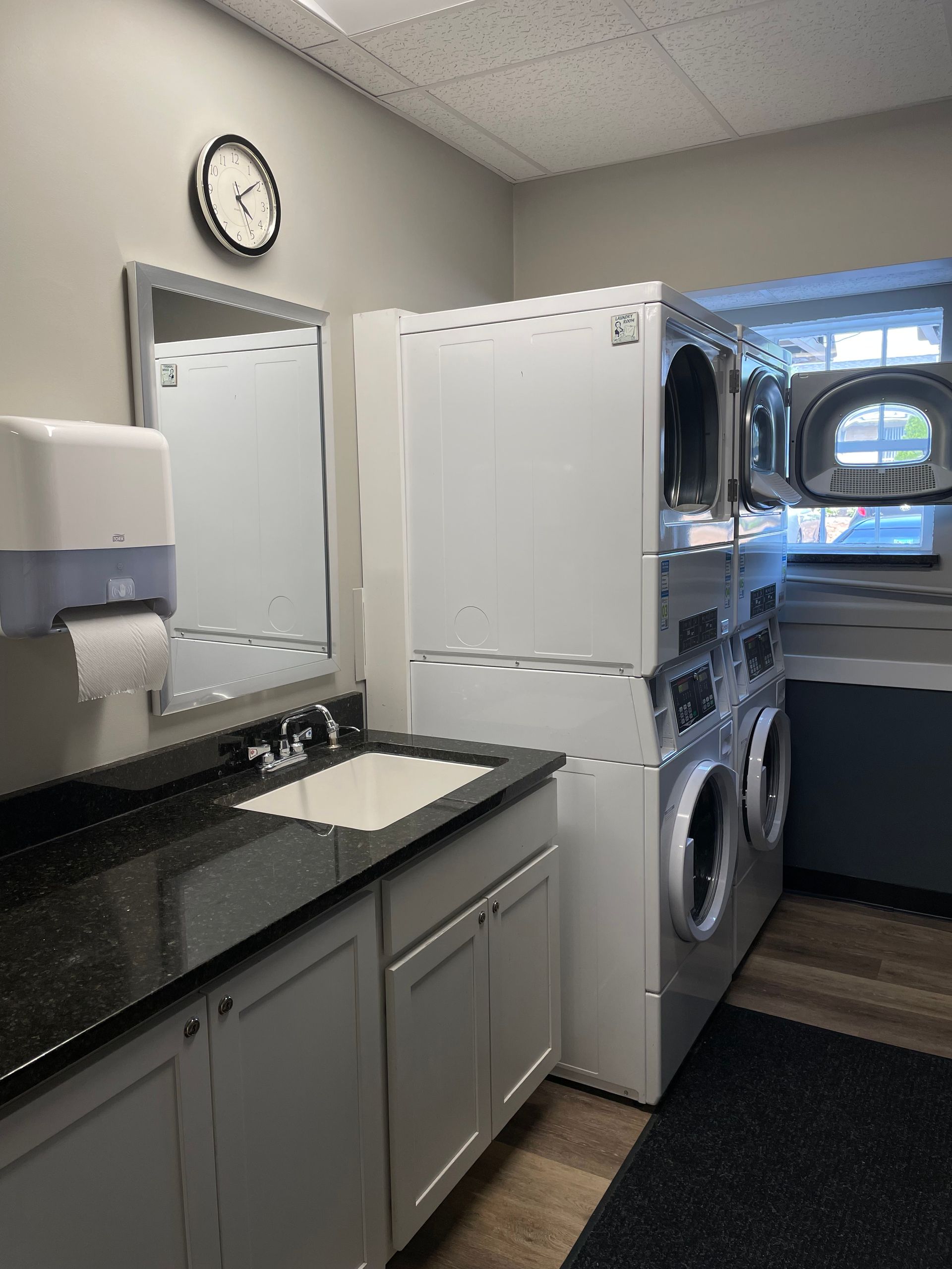 a laundry room with a sink , washer and dryer stacked on top of each other .