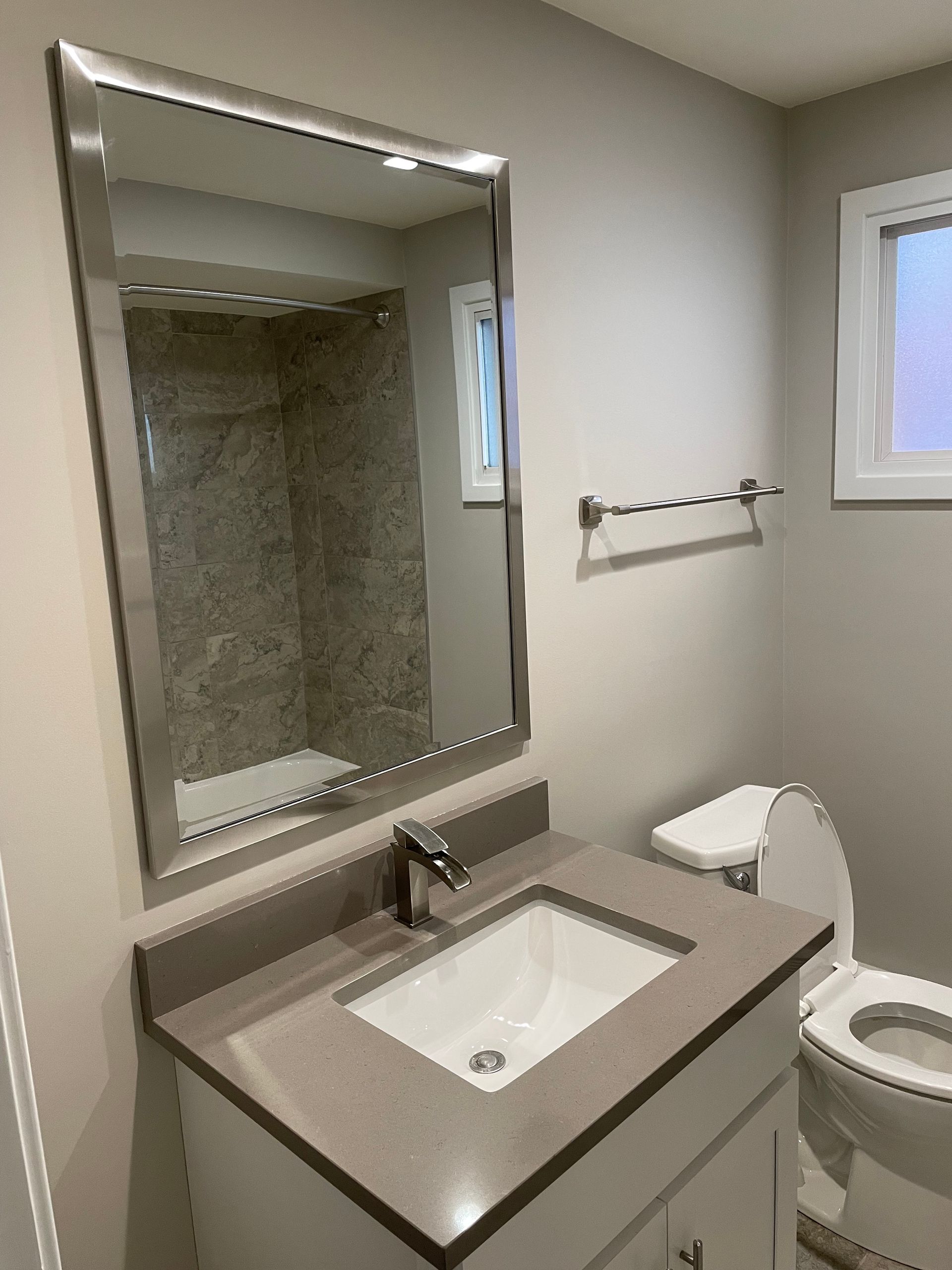 a bathroom with a sink , toilet and mirror .