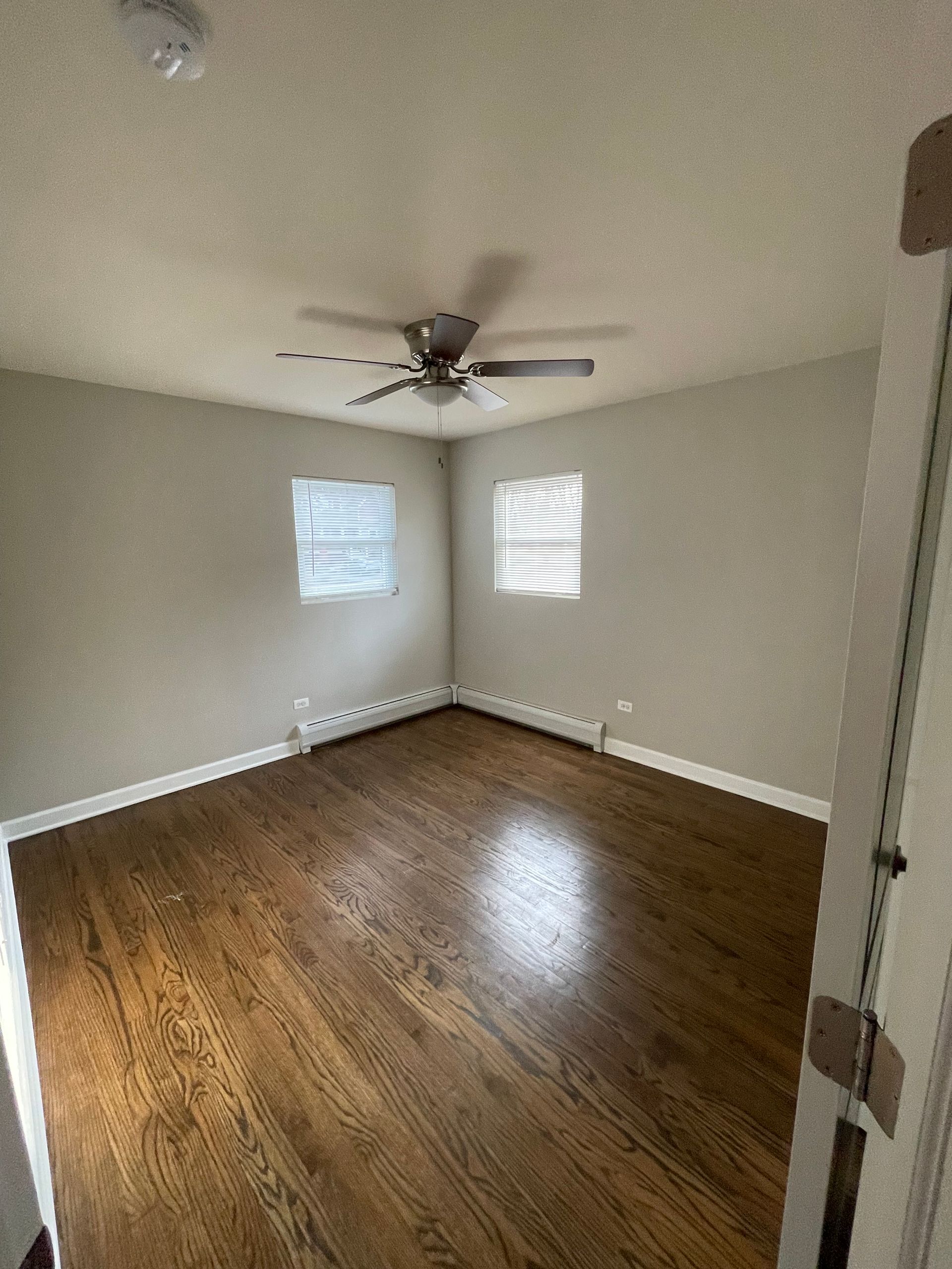 an empty room with hardwood floors and a ceiling fan .