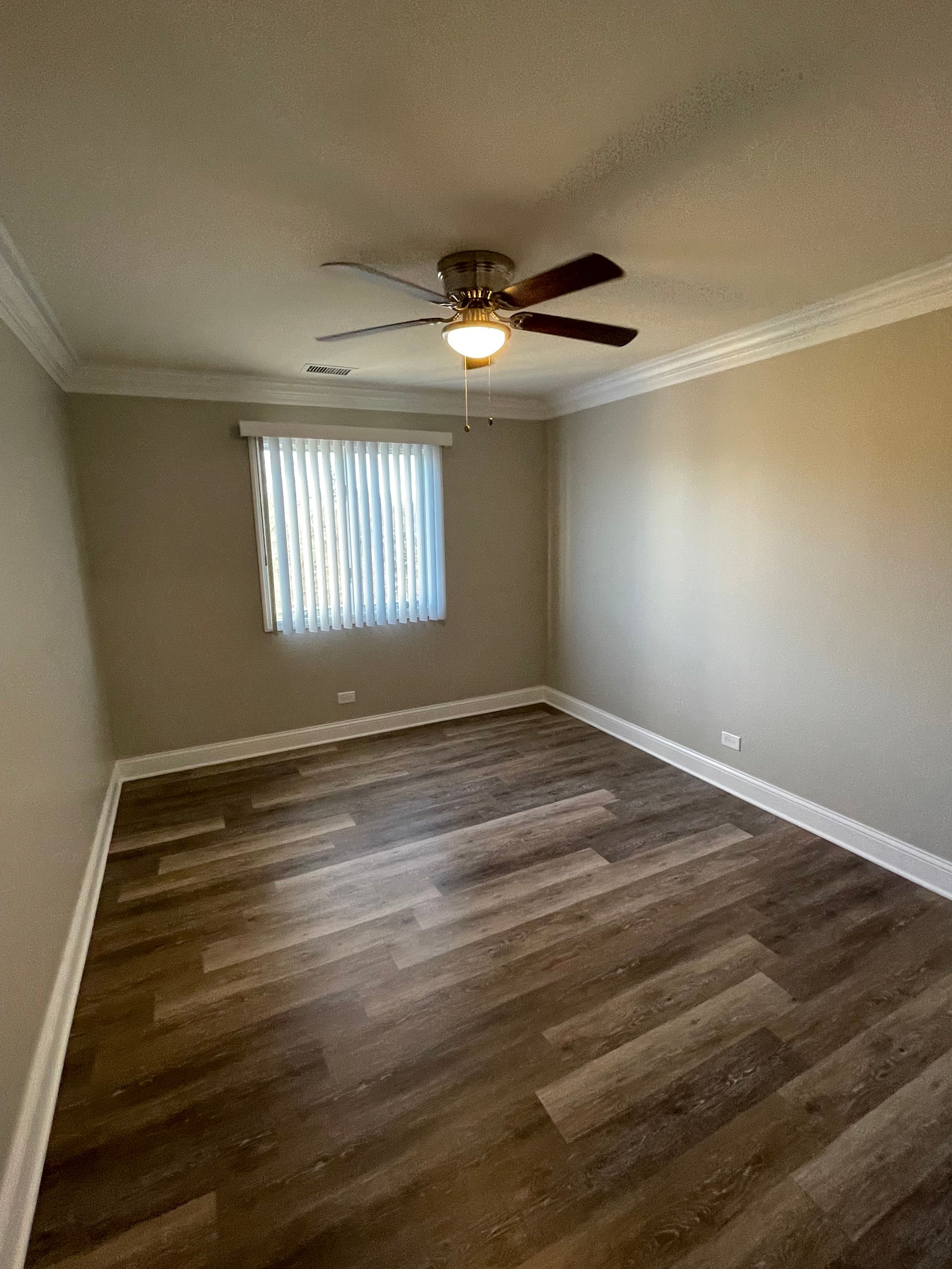 an empty bedroom with a ceiling fan and a window .