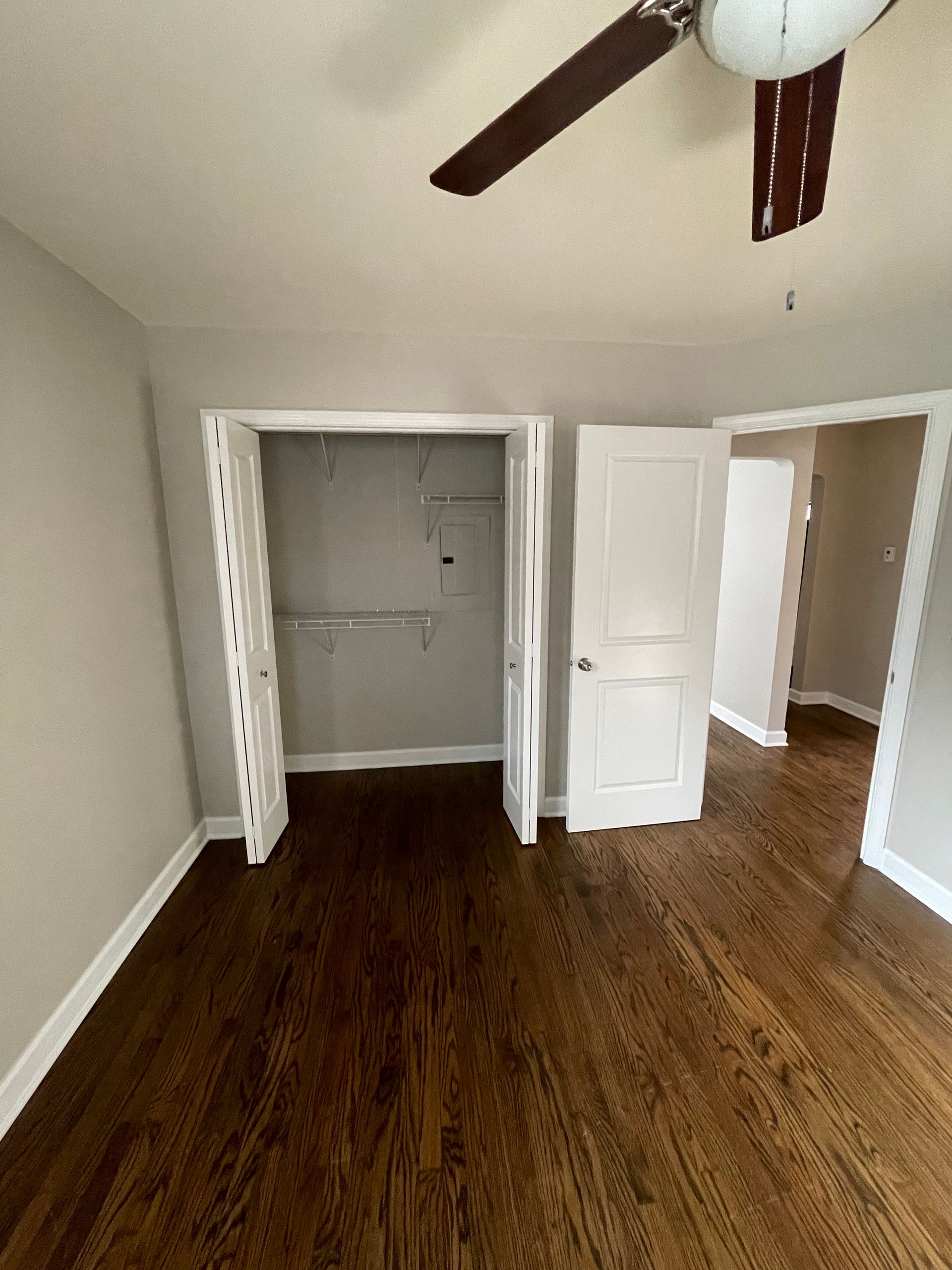 an empty room with hardwood floors and a ceiling fan .