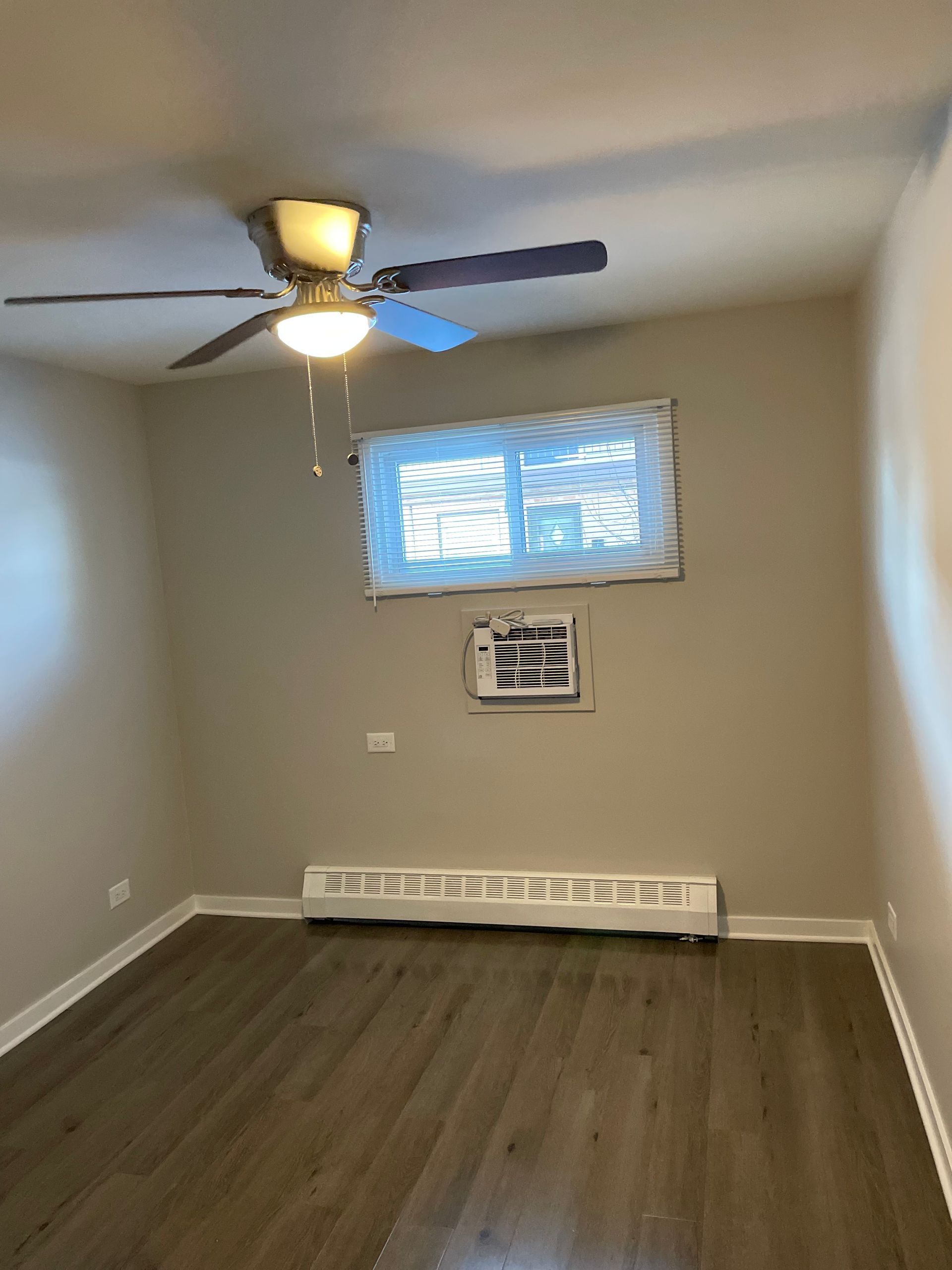an empty room with a ceiling fan and a window .