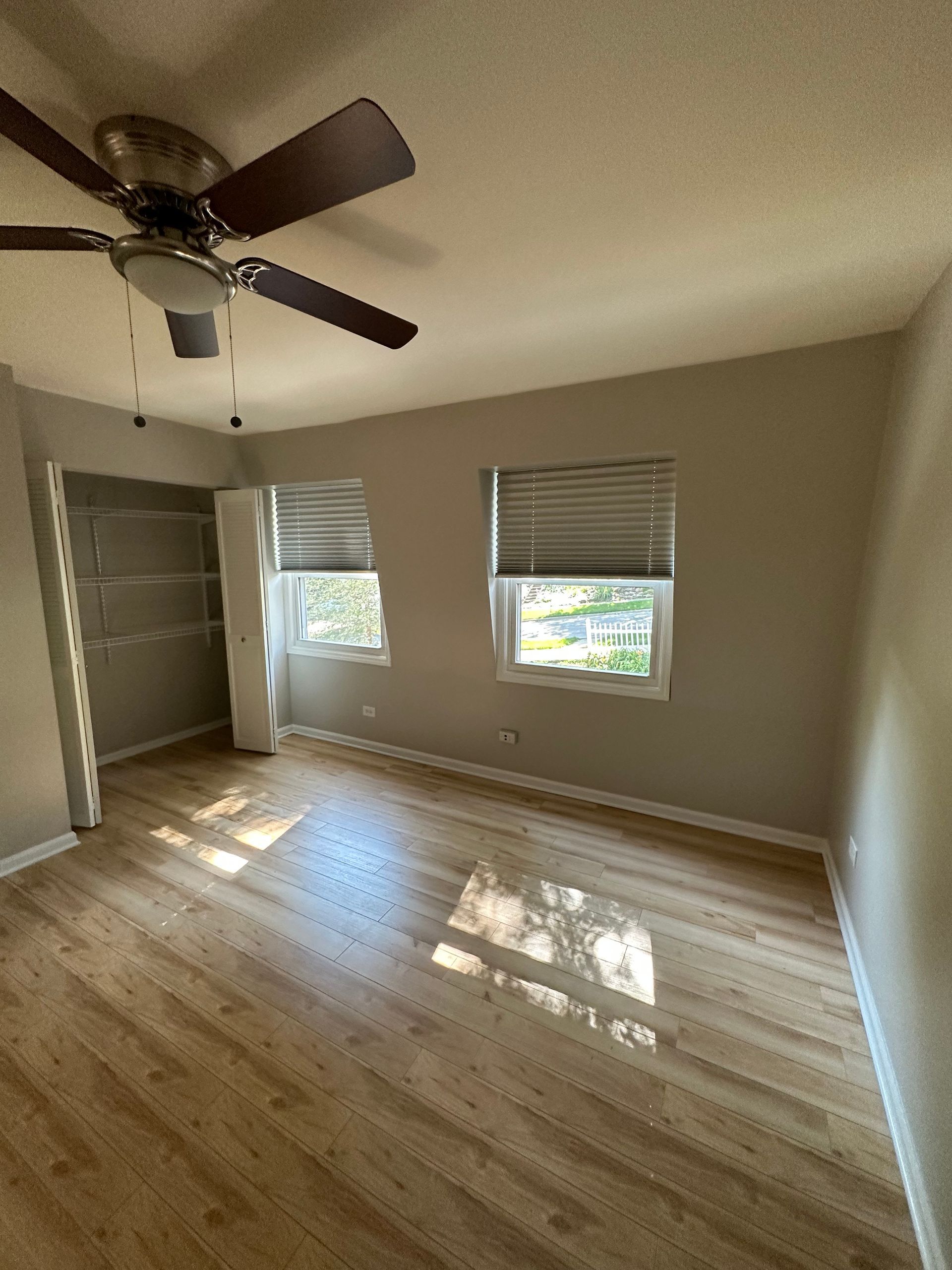 an empty room with hardwood floors and a ceiling fan .