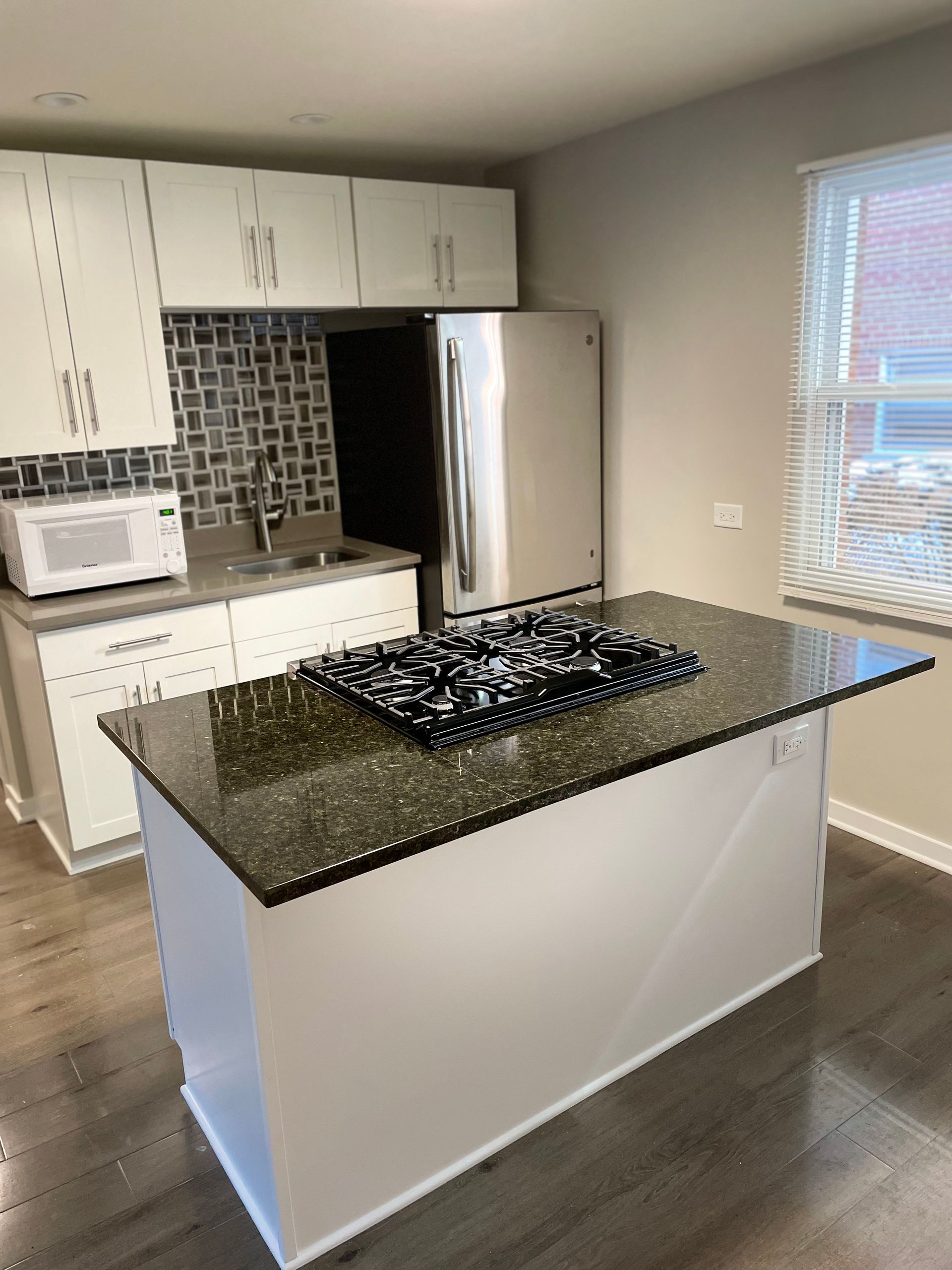 a kitchen with a stove top oven , refrigerator , sink and microwave .