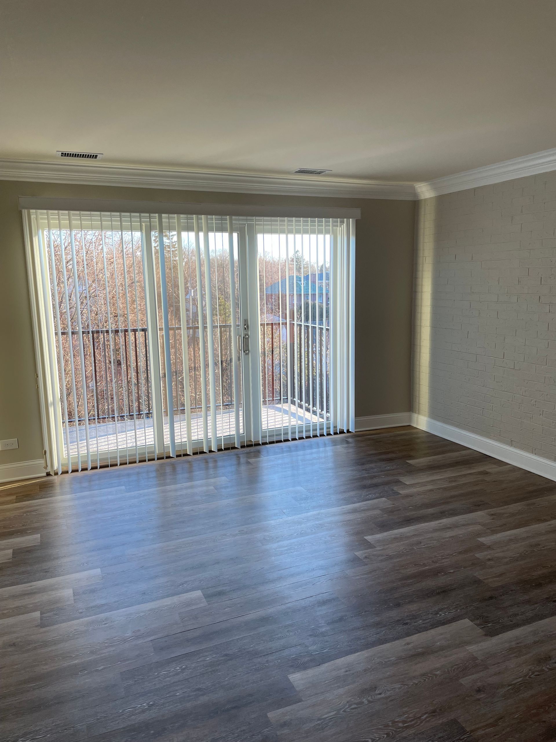 an empty living room with hardwood floors and sliding glass doors .