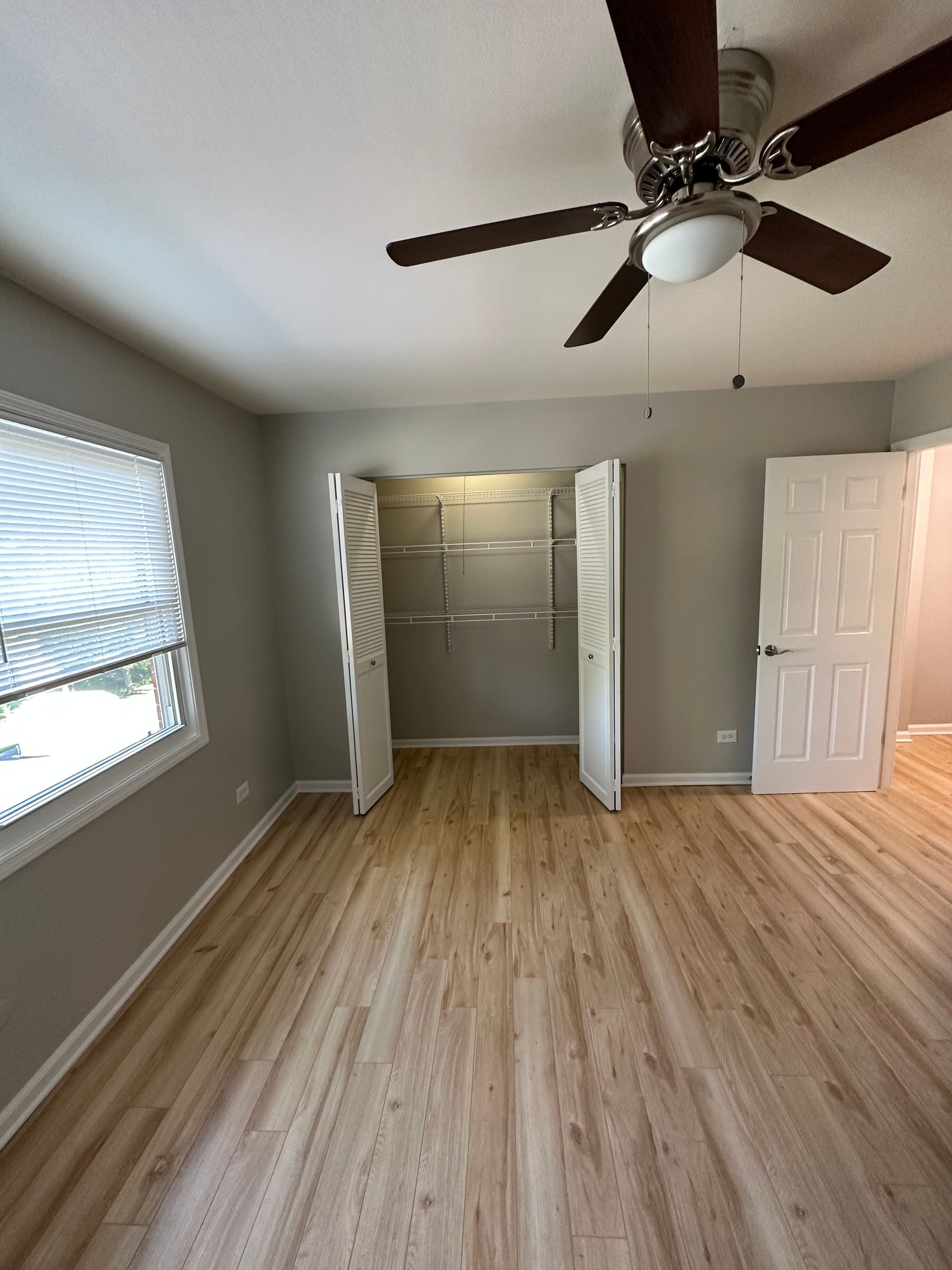 an empty bedroom with hardwood floors and a ceiling fan