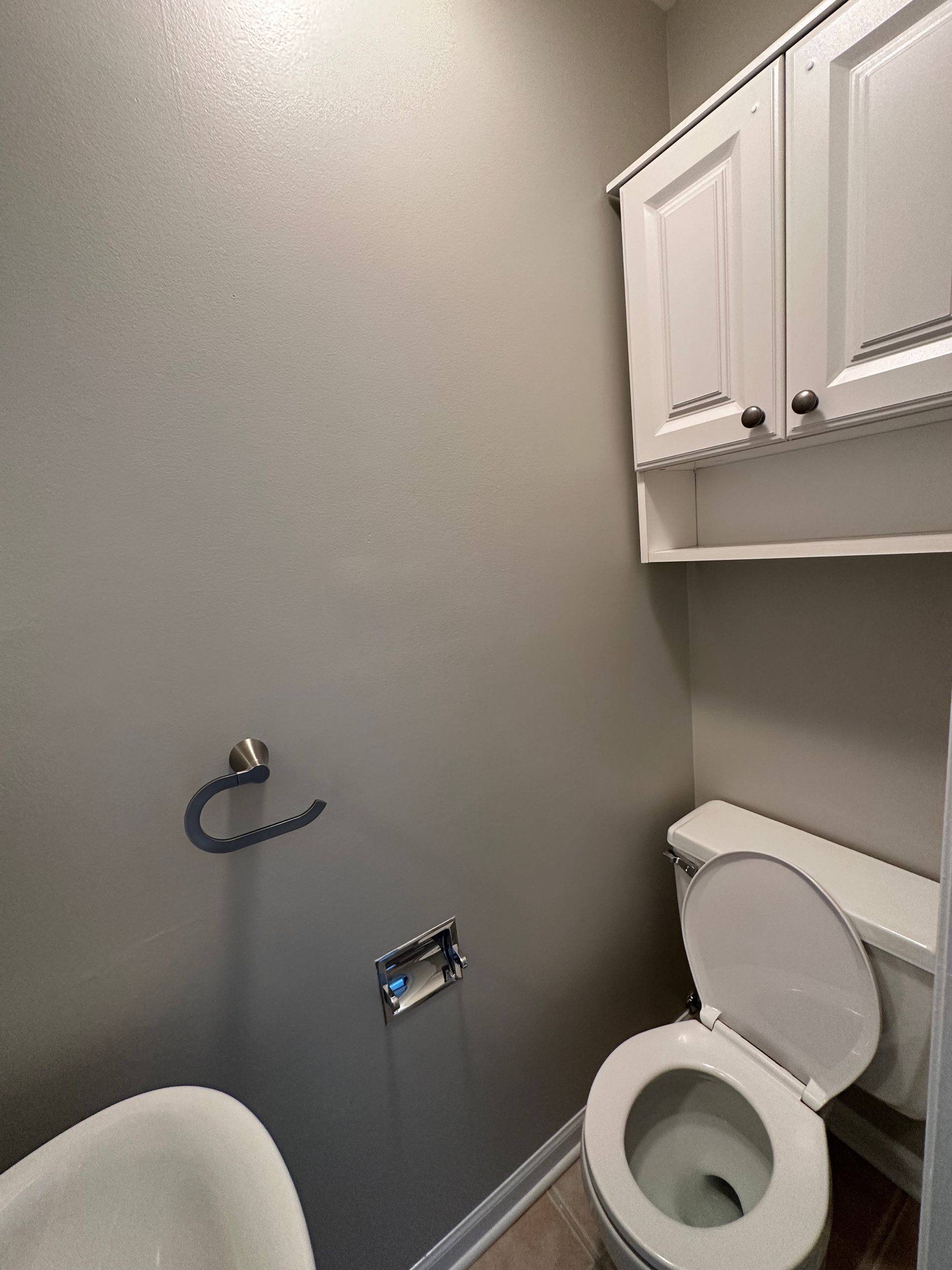a bathroom with a toilet , sink , and cabinets .