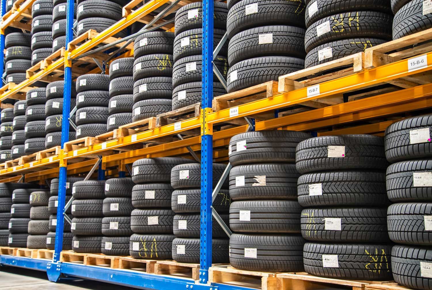 Tires stacked on red shelves in a store, close up view with focus on tire treads.