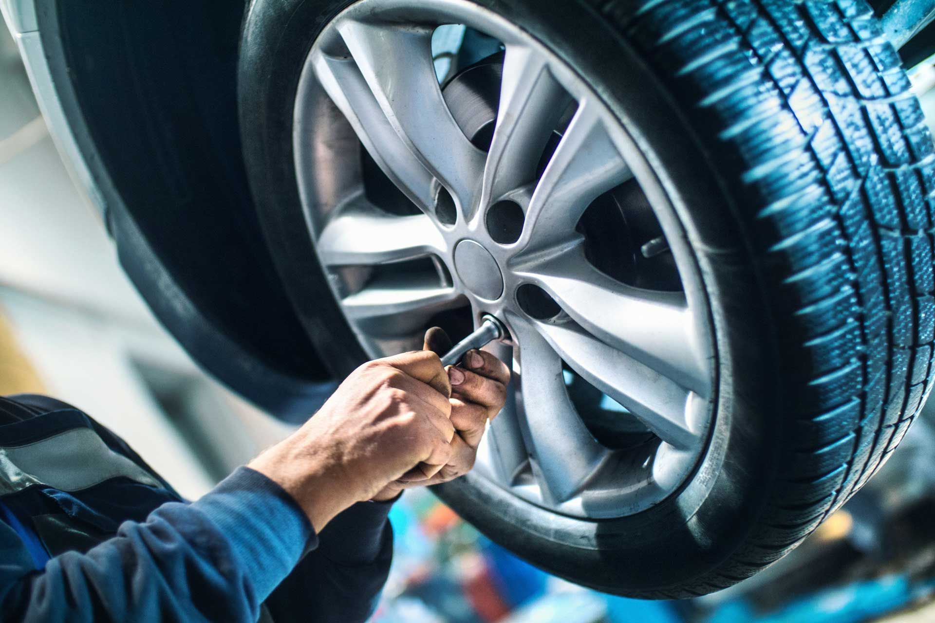 Mechanic tightening lug nuts on a car tire, close-up view.