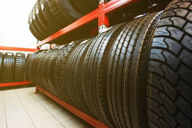 Tires stacked on red metal shelves in a tire shop.