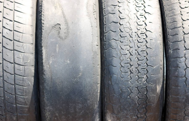 Four worn car tires stacked side-by-side, showing various tread patterns and wear.