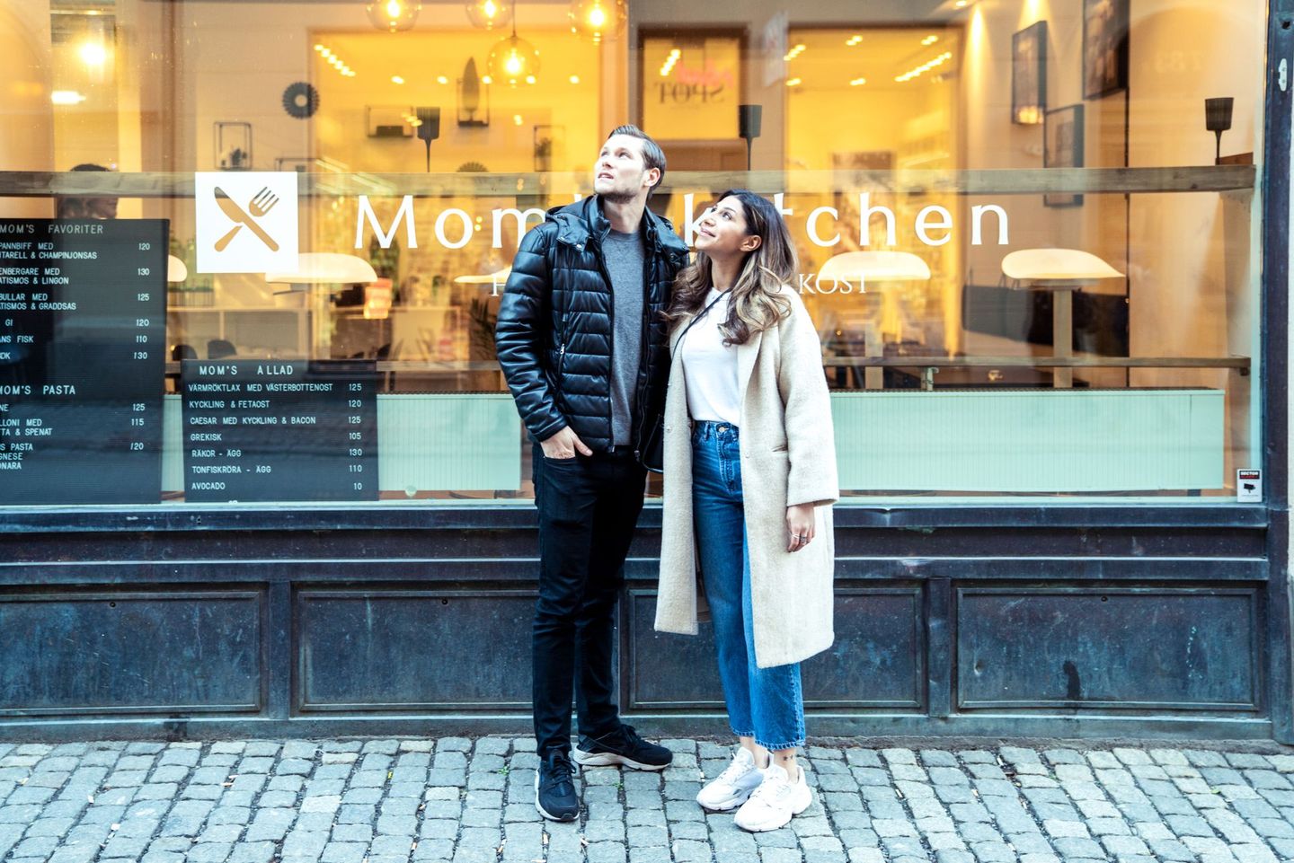 a man and a woman are standing in front of a restaurant .