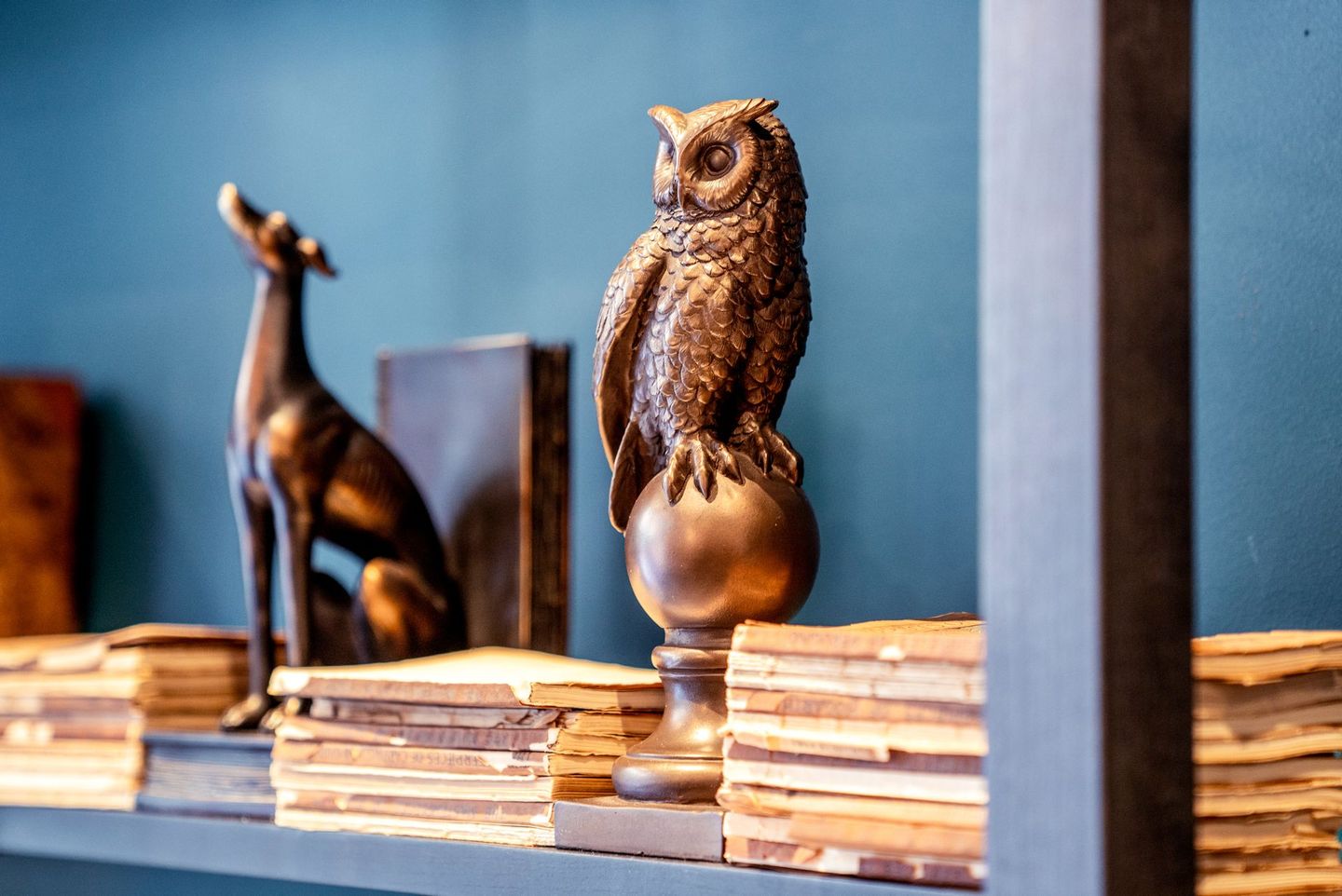 a shelf with a statue of an owl sitting on top of a stack of books .