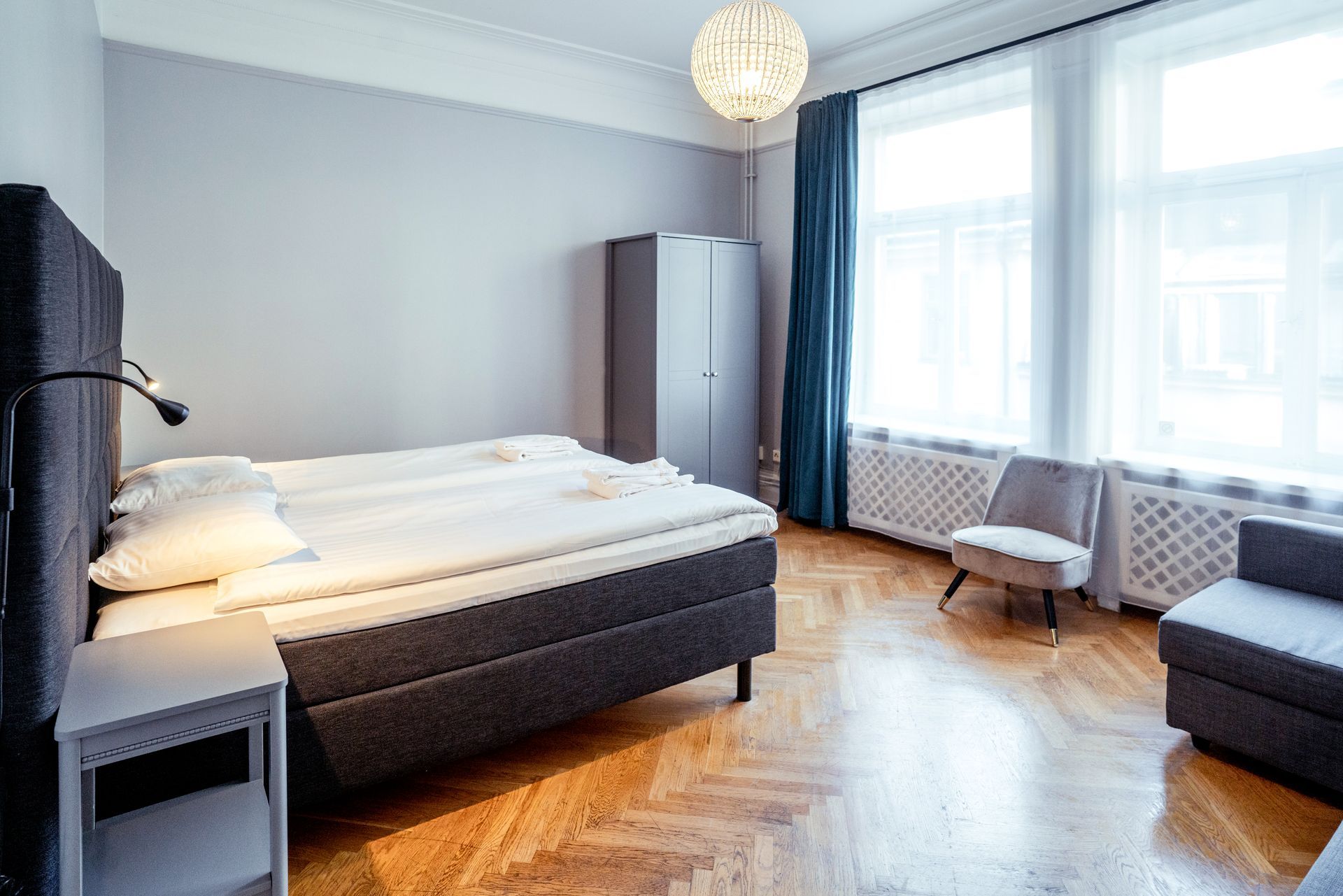a bedroom with a bed , chair , nightstand and window .