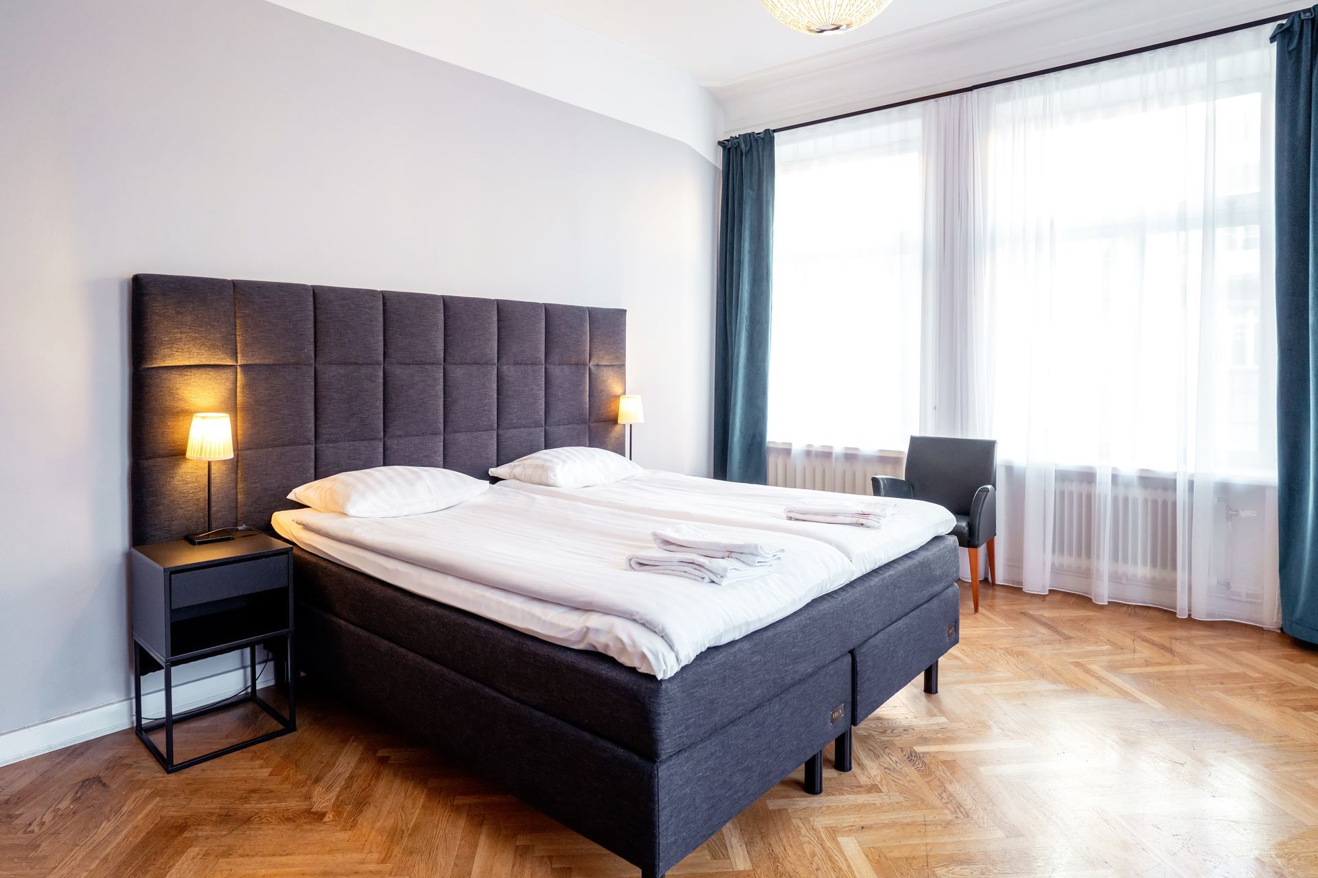 a hotel room with two beds , a chair and a window .