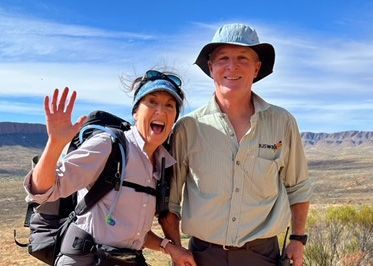 David and Kathleen smiling and waving on top of mountain in Australian wilderness