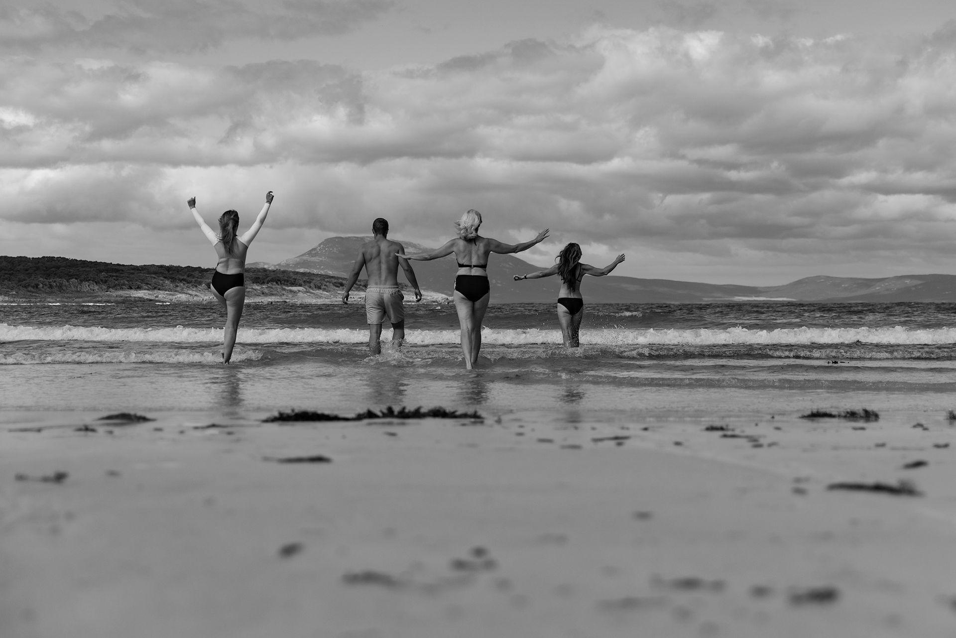 Four people embracing the ocean in winter on Flinders Island.