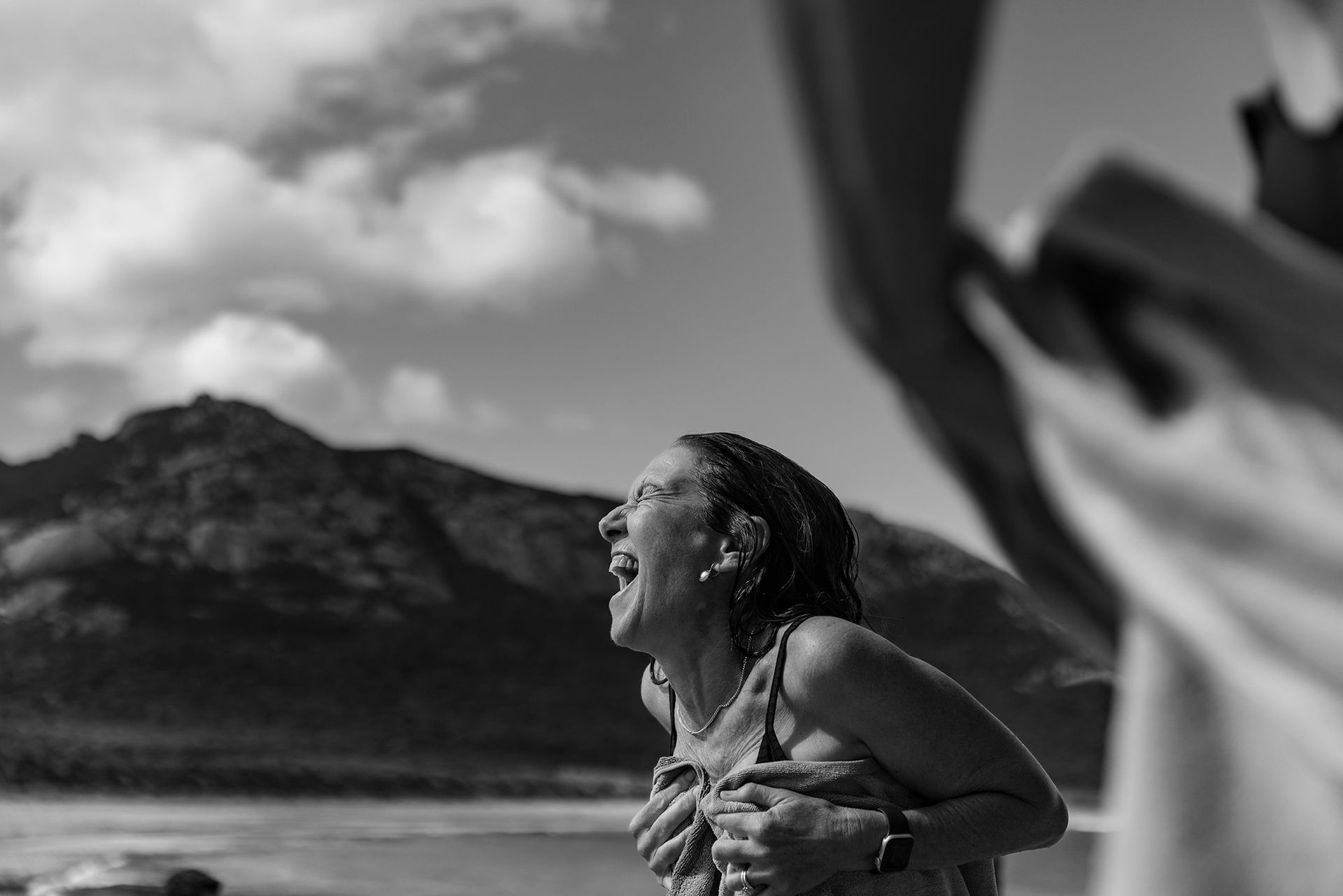 A woman smiling and laughing on a remote beach on Flinders Island.