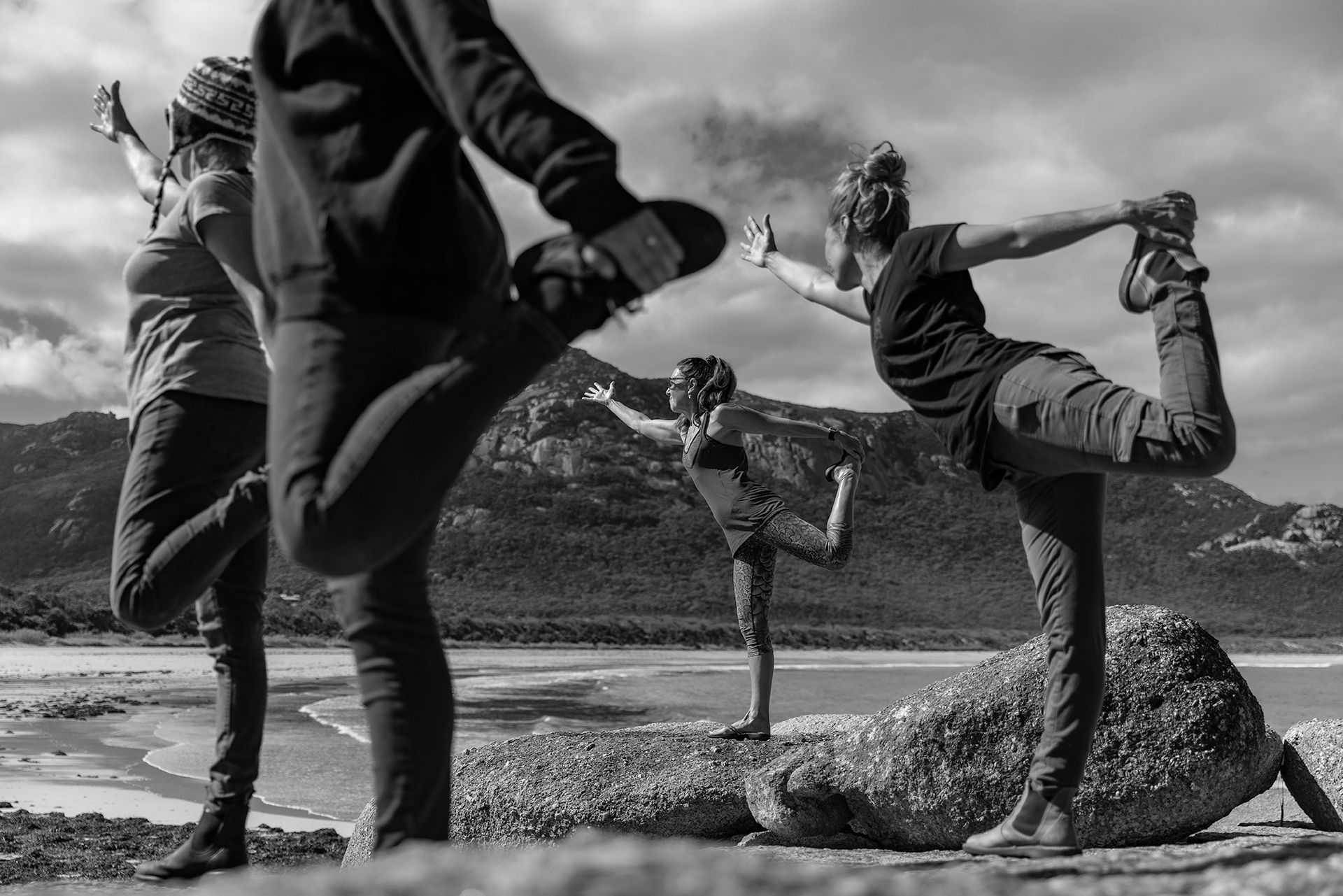 Four people are doing yoga on the beach at Flinders Island.