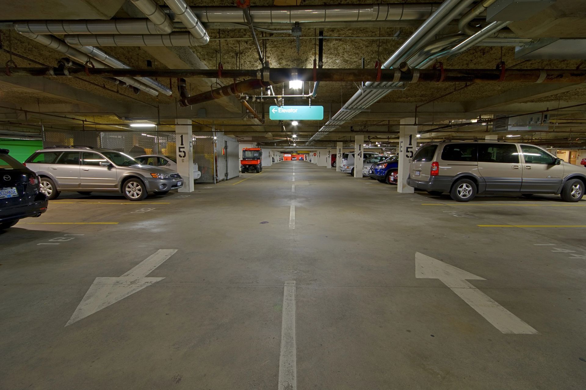 A parking garage filled with cars and arrows pointing in opposite directions.