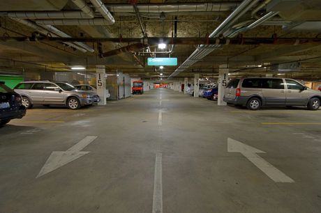 A parking garage filled with cars and arrows pointing in opposite directions.