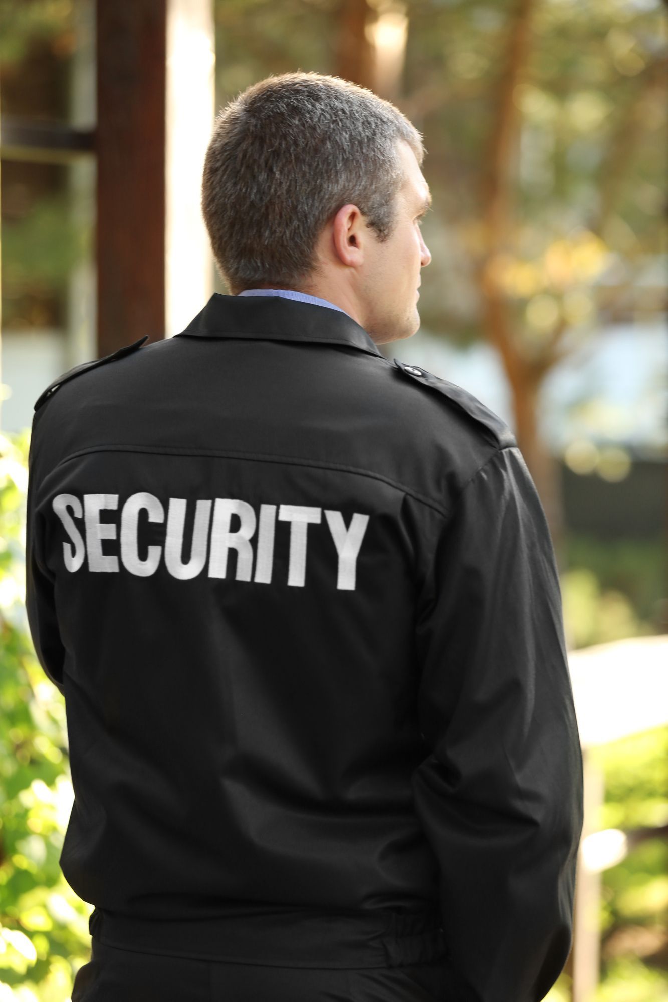 A security guard wearing a black jacket with the word security on the back.