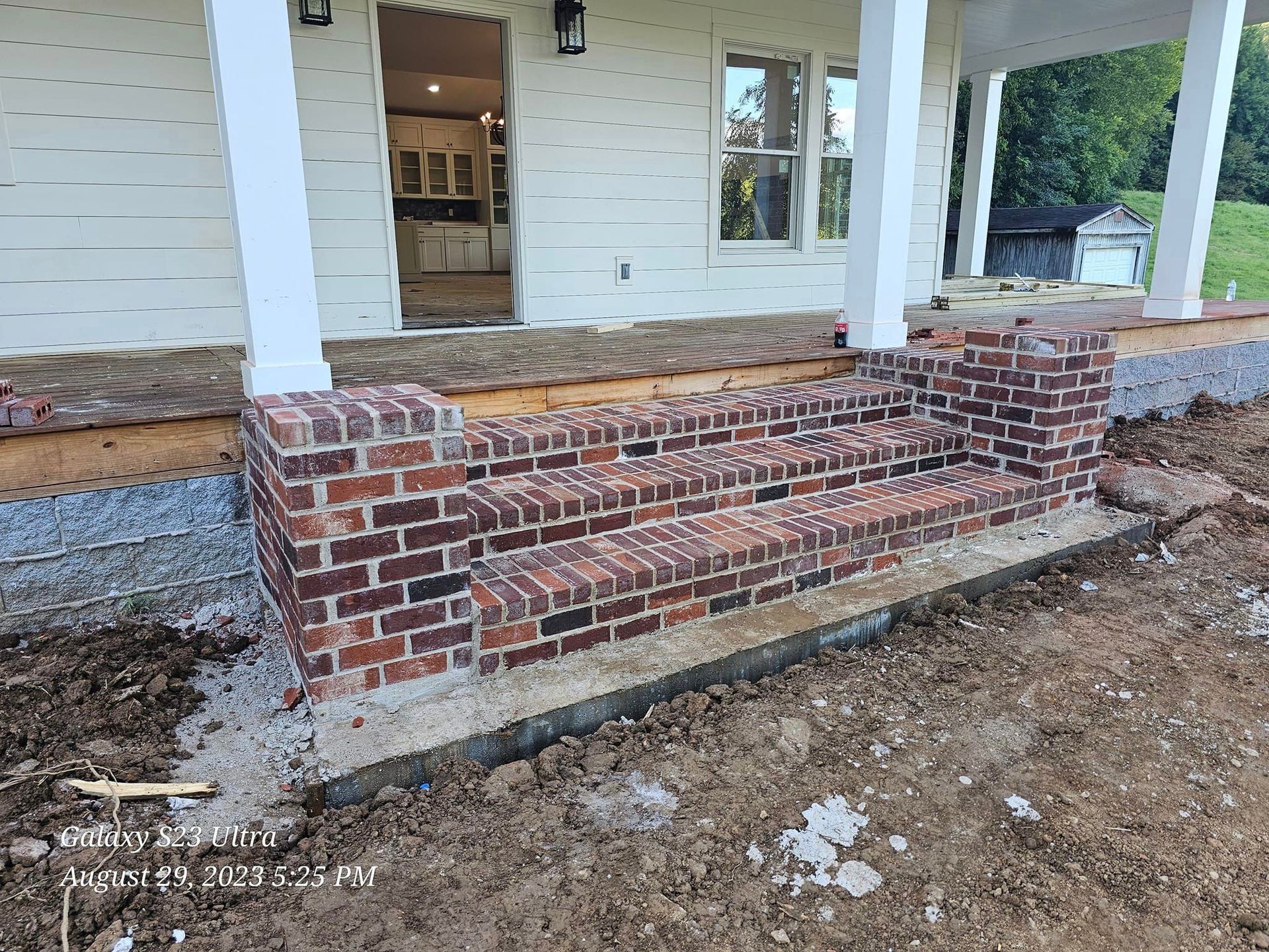 Brick steps leading to a house's front door on a porch.