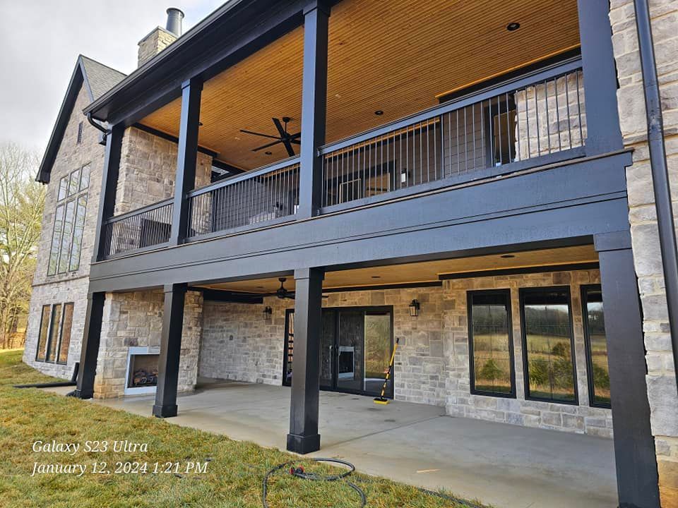 Two-story house with a covered deck and black columns, brick exterior, and a concrete patio.