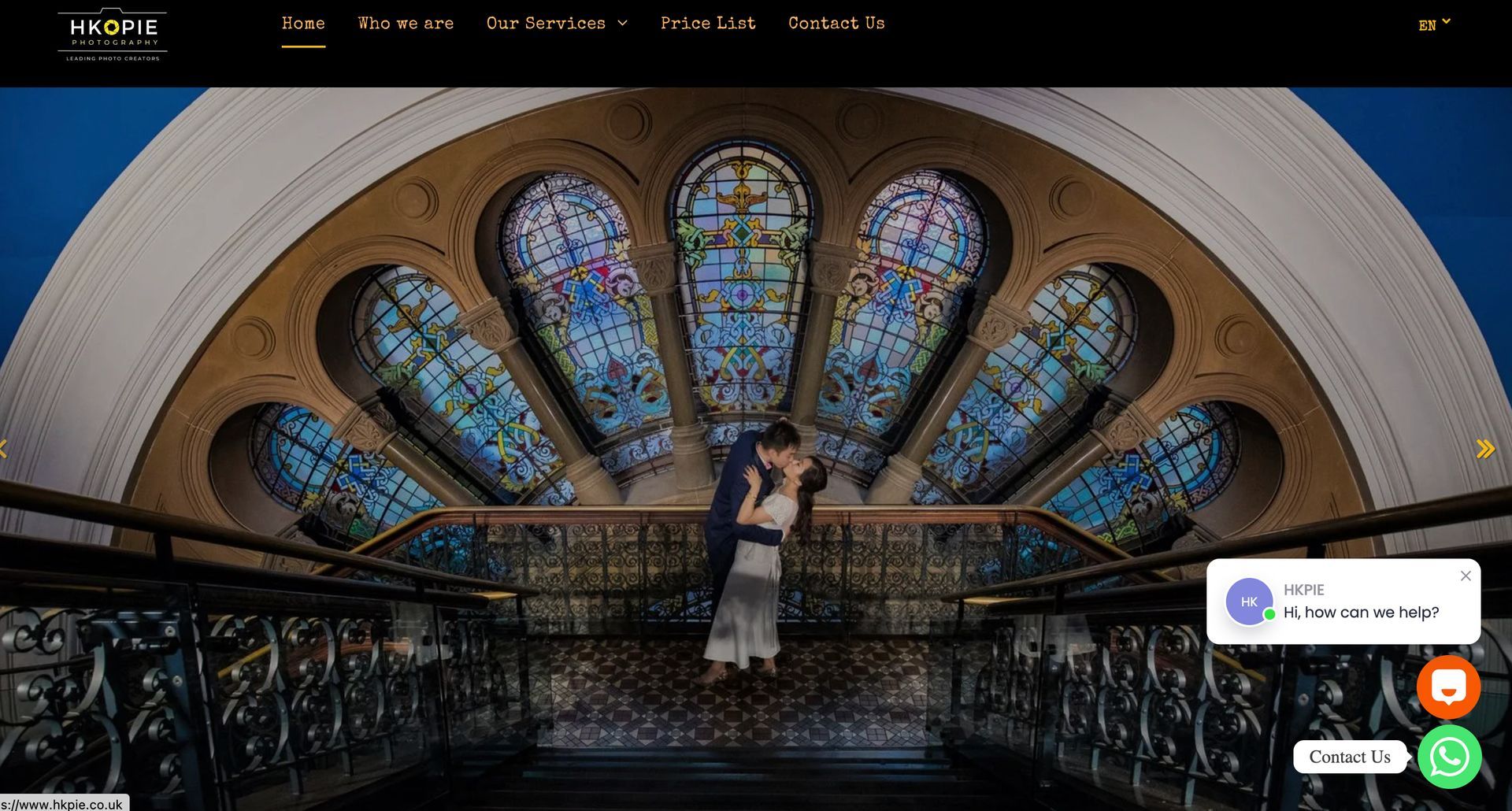 Couple embracing on a balcony with stained glass windows overhead, elegant setting.