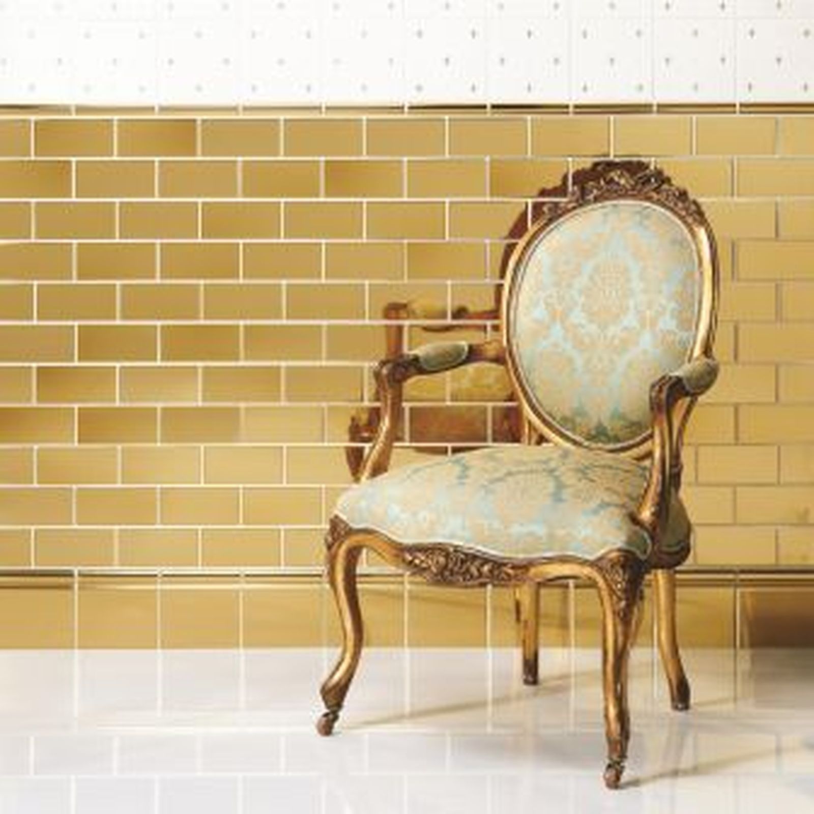 Ornate gold chair against a tiled wall.