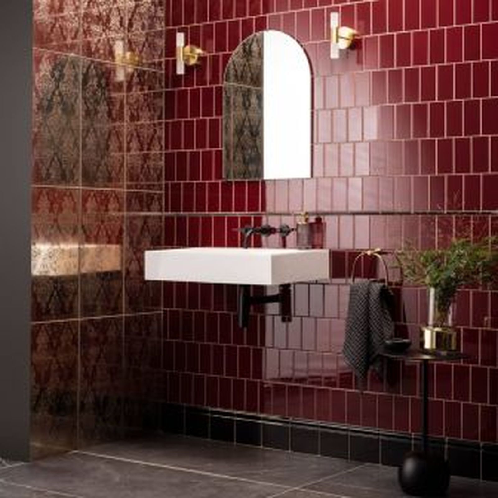 Red tiled bathroom with a white sink, mirror, and gold fixtures.