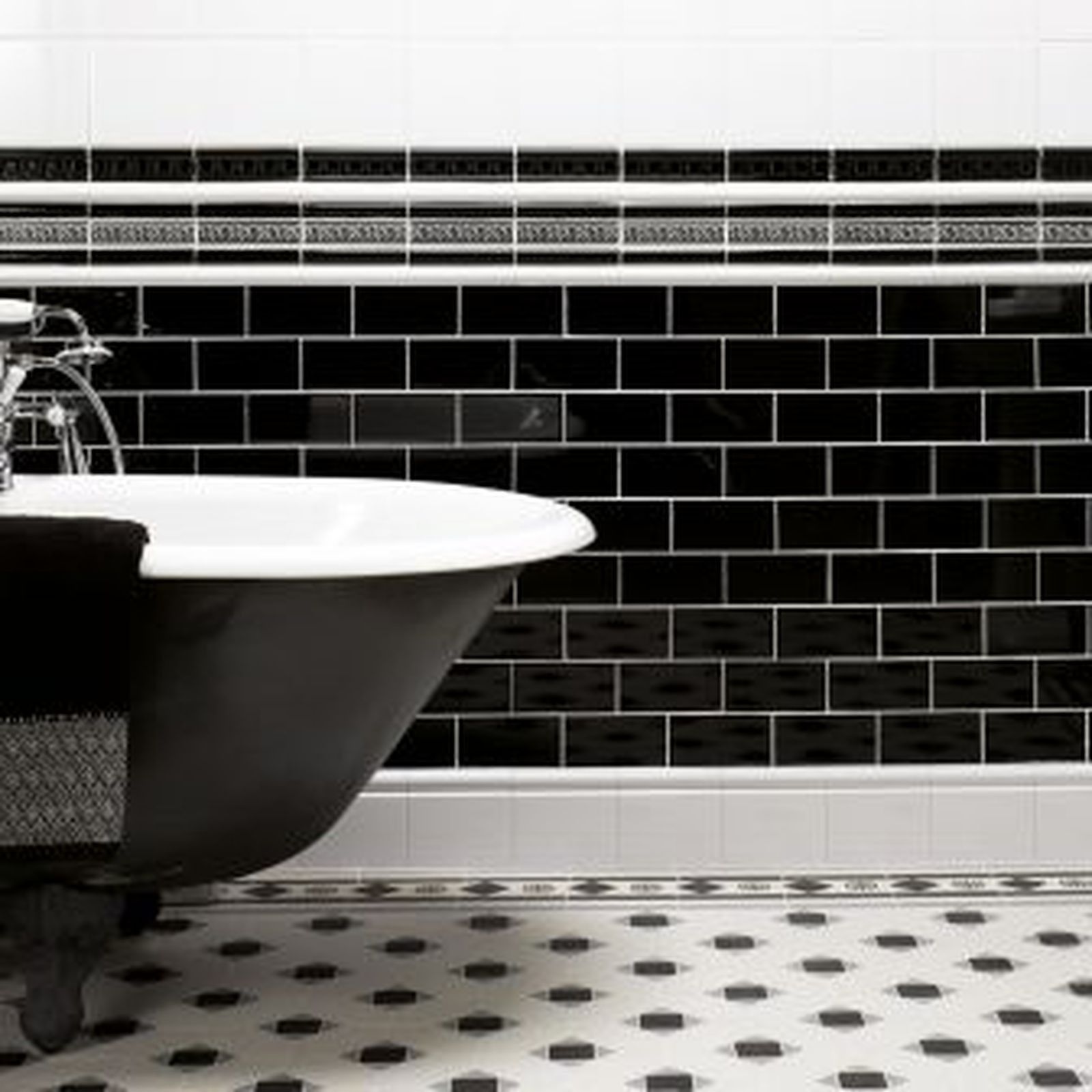 Black and white bathroom with a clawfoot tub and black subway tile wainscot.