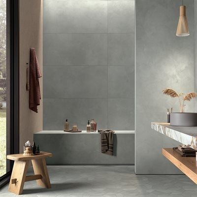 Bathroom with gray tiles, a wooden stool, and a built-in tub. Natural light streams in.