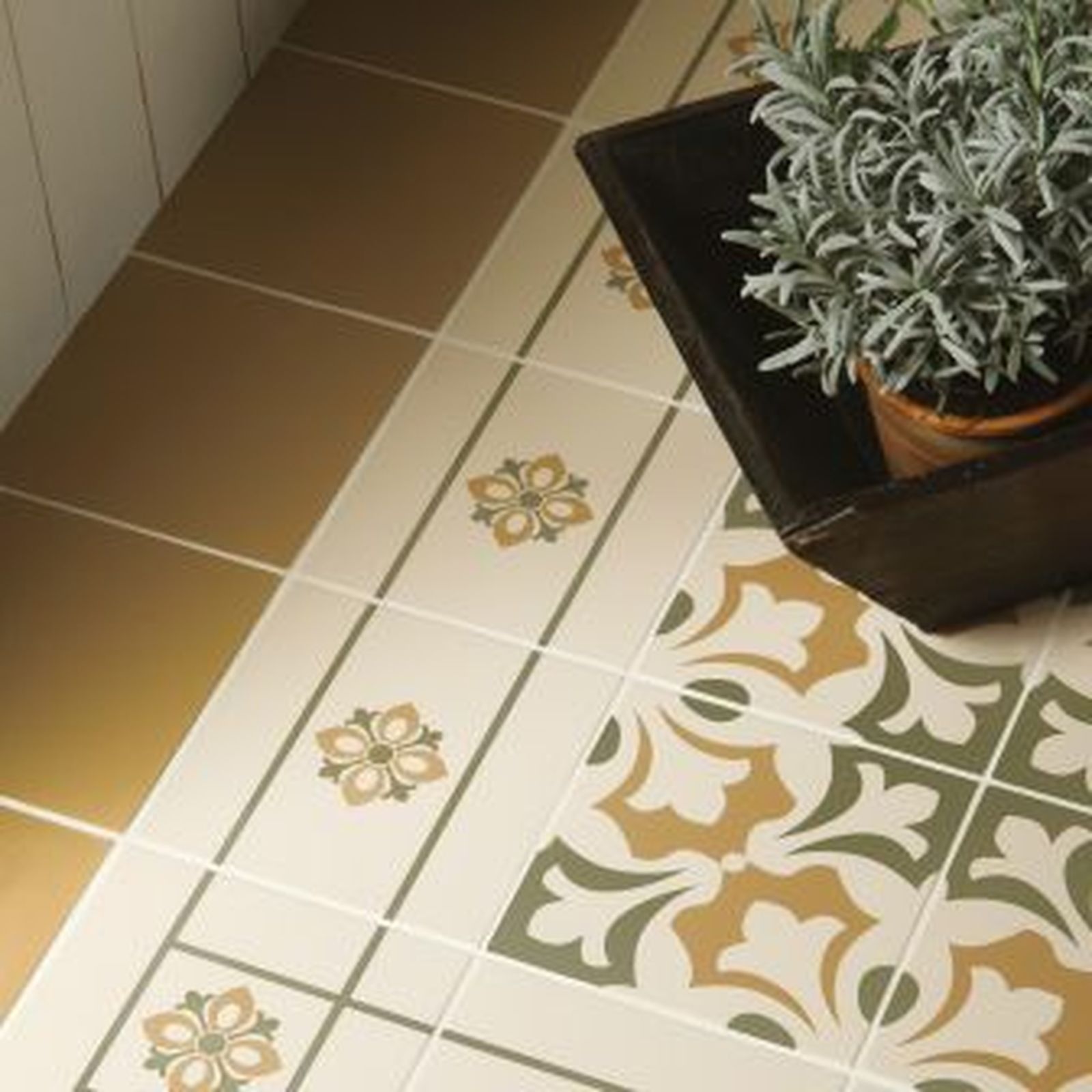 Tile floor with brown, cream, and green floral patterns. Plant in wooden container sits on tiles.