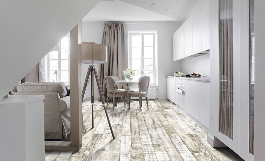 White kitchen and dining area with weathered wood floors, neutral tones, and natural light.