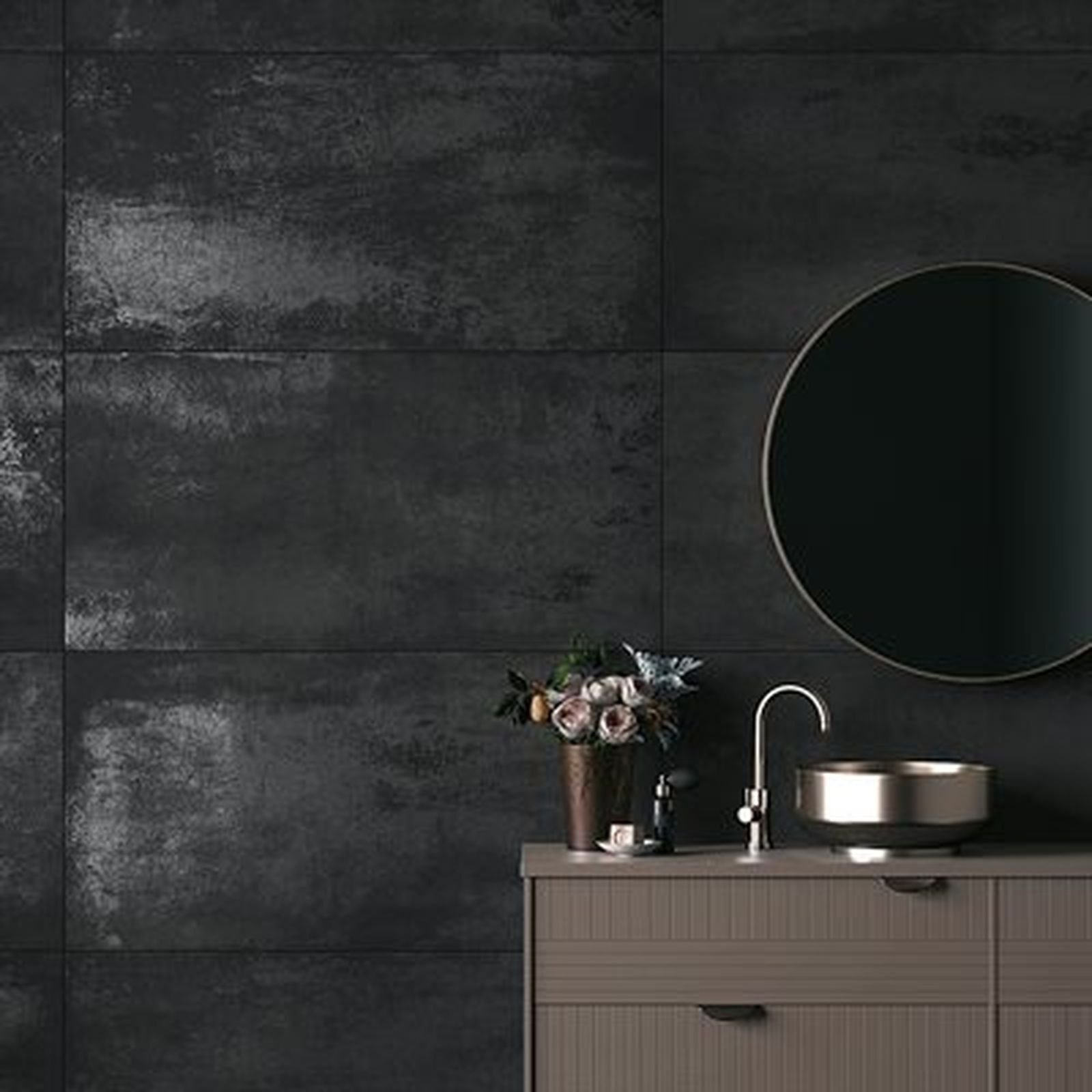 Dark bathroom with black textured tile wall, round mirror, wood vanity, and silver faucet.