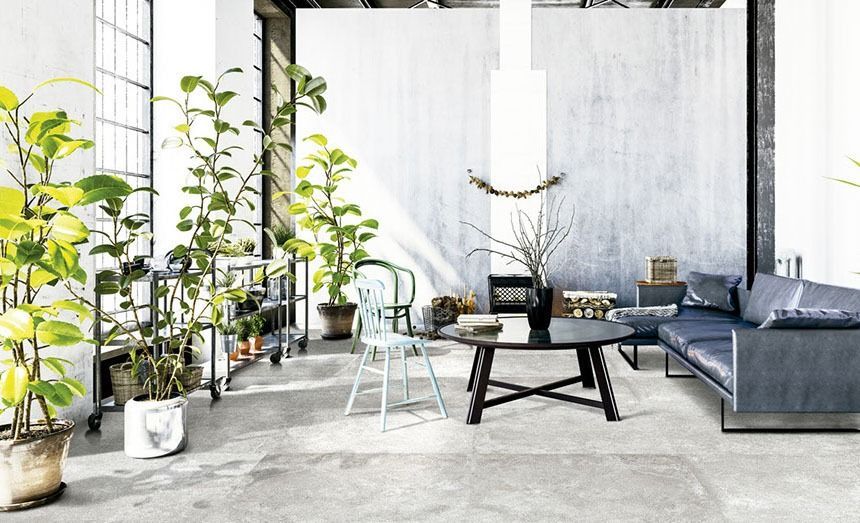 Industrial-style living room with potted plants, a blue sofa, and a black coffee table.