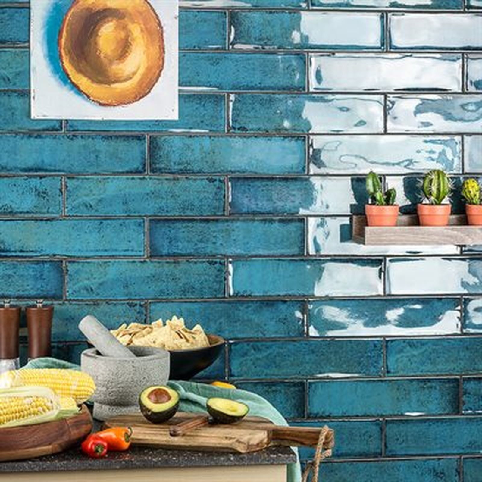 Turquoise brick-like tile backsplash in kitchen, with food prep area: avocados, corn, chips, and cacti.