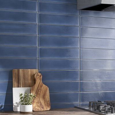 Blue ribbed tile backsplash in a kitchen with cutting boards and a plant.