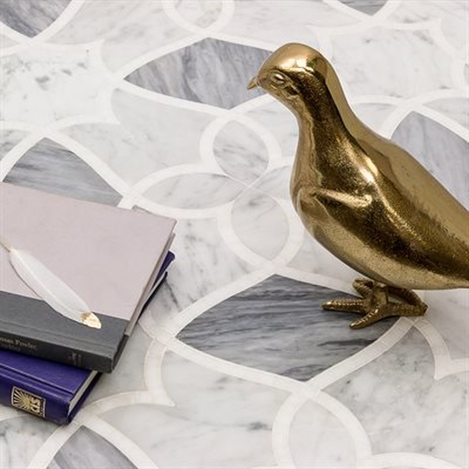 Gold bird statue on marble tile with books.
