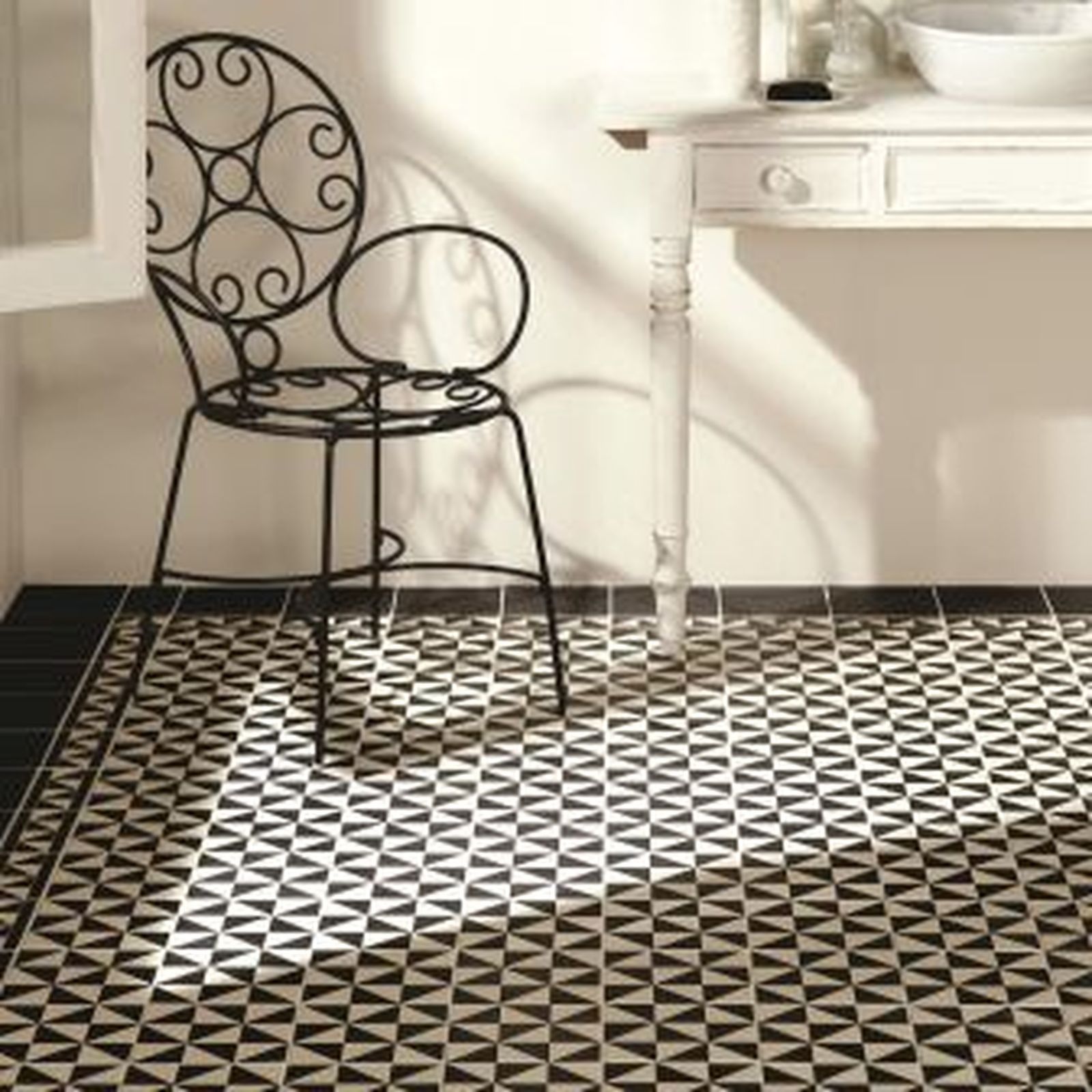 Black and white patterned tile floor with a decorative metal chair and small white table.