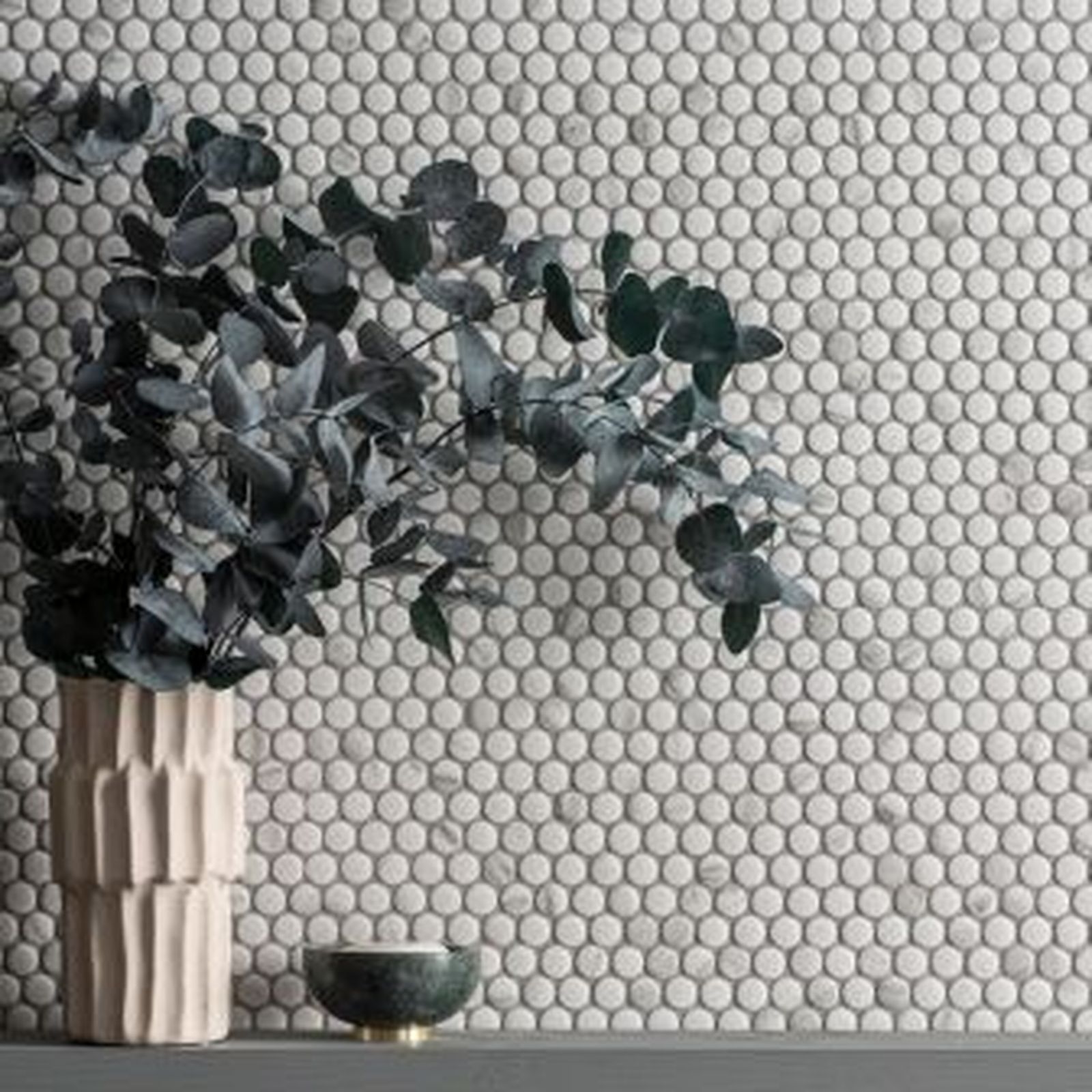 White penny tile backsplash with a vase of eucalyptus and small bowl.