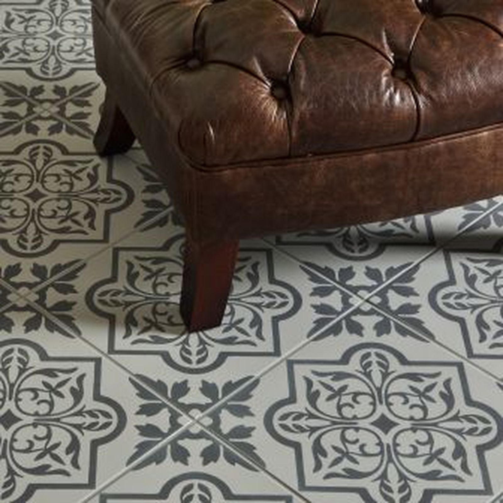 Brown leather ottoman on patterned gray and white tile floor.