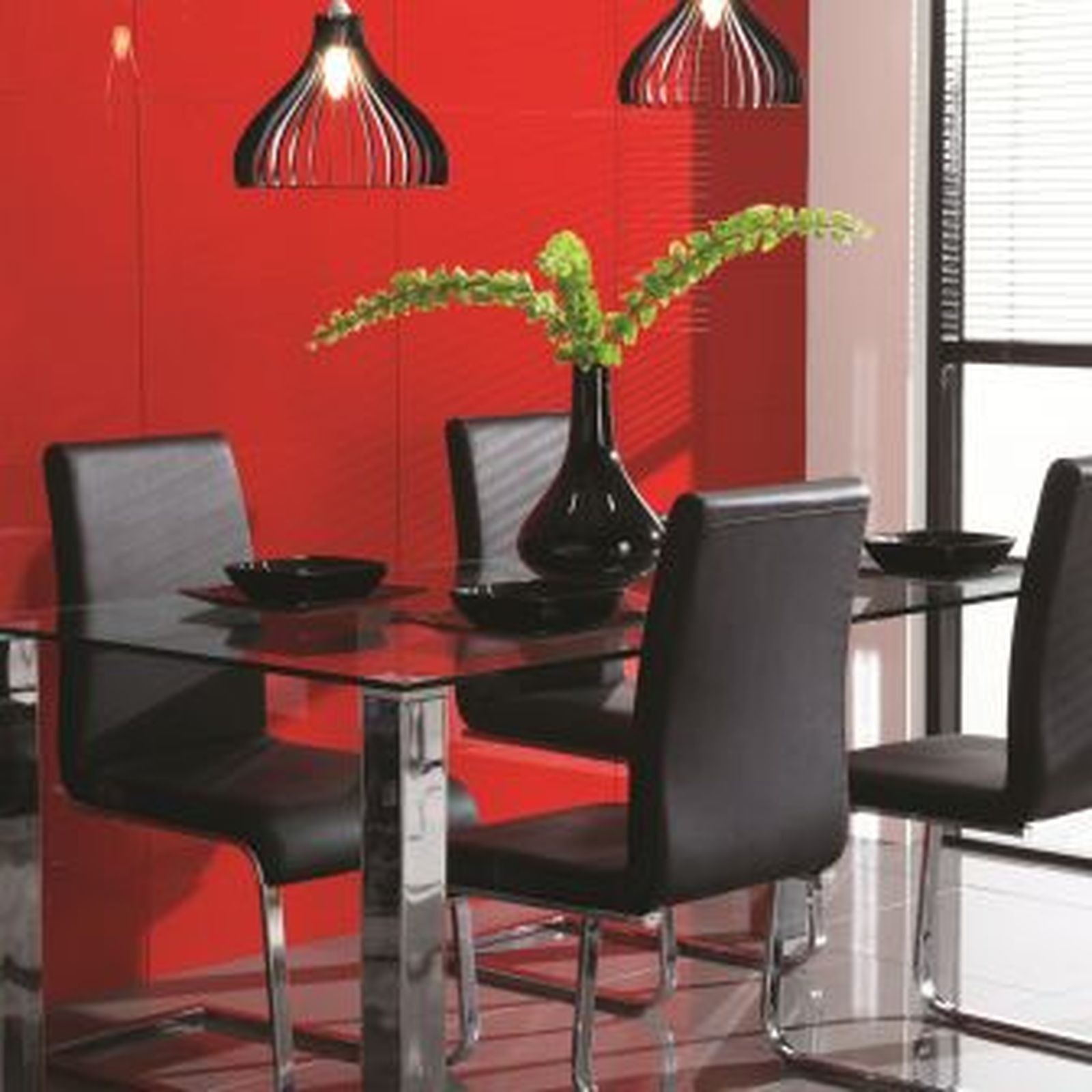 Dining table with black chairs, red wall, and pendant lights.