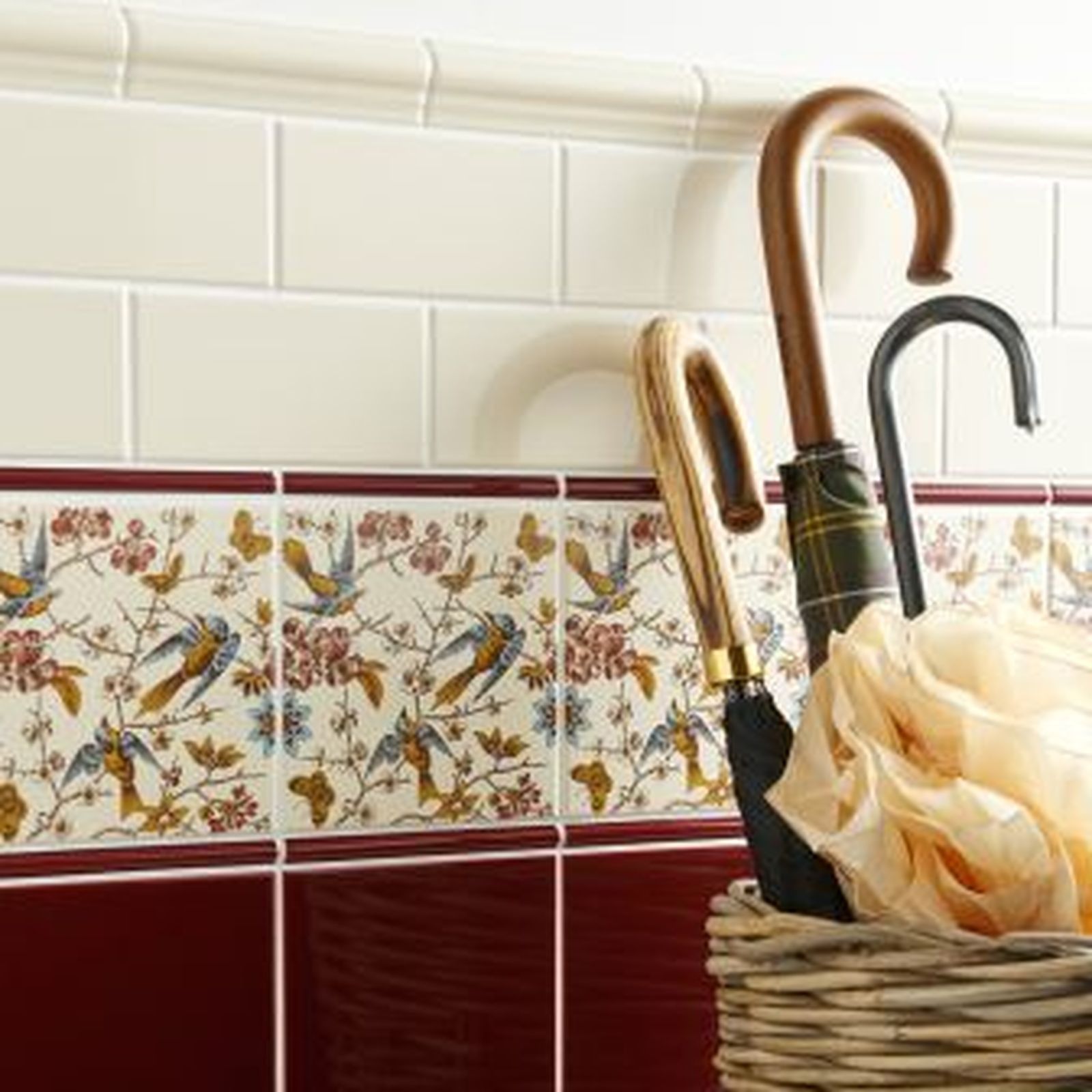 Wall tiled with decorative border, basket of umbrellas.