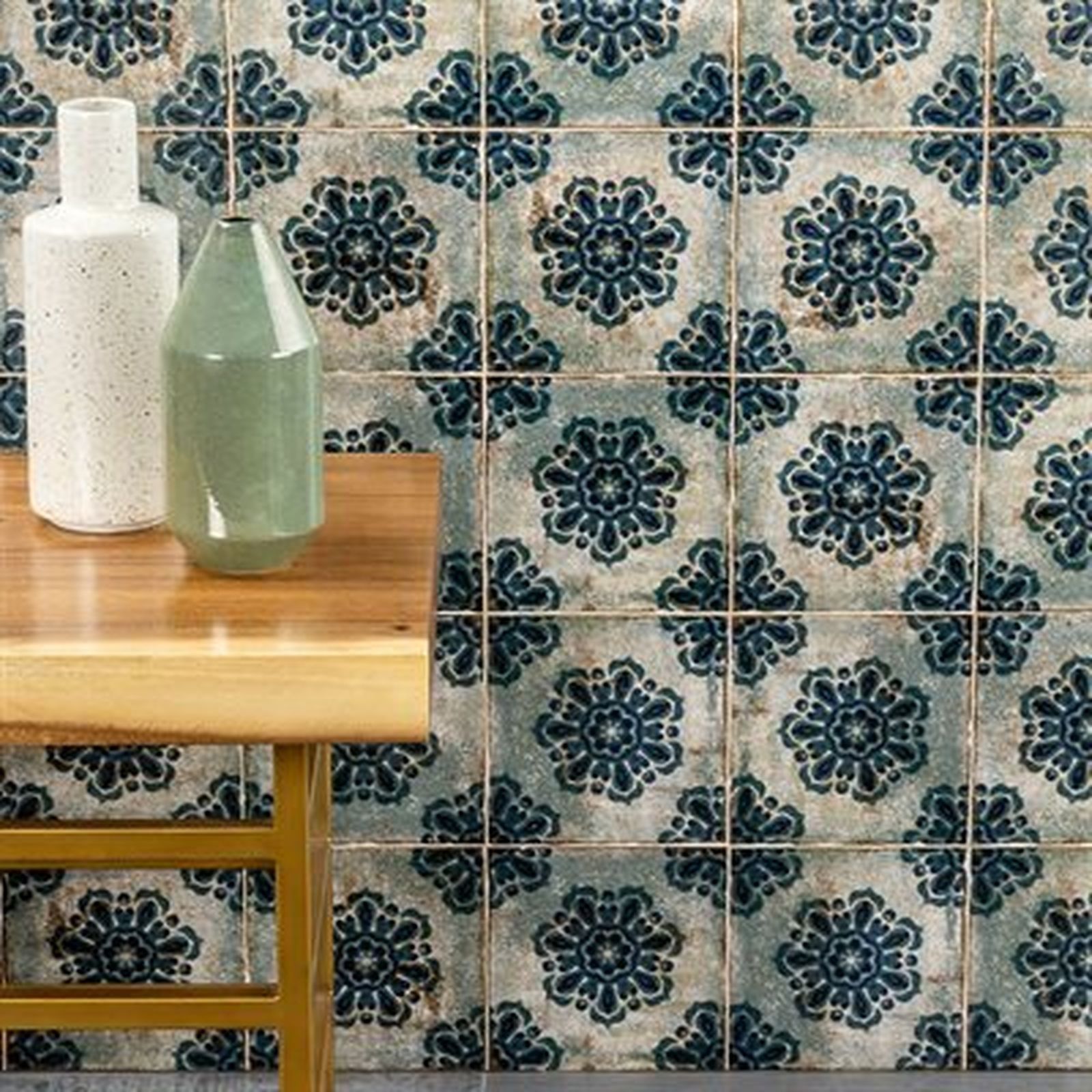 Two vases on a table, with patterned blue and white tiles on the wall behind them.