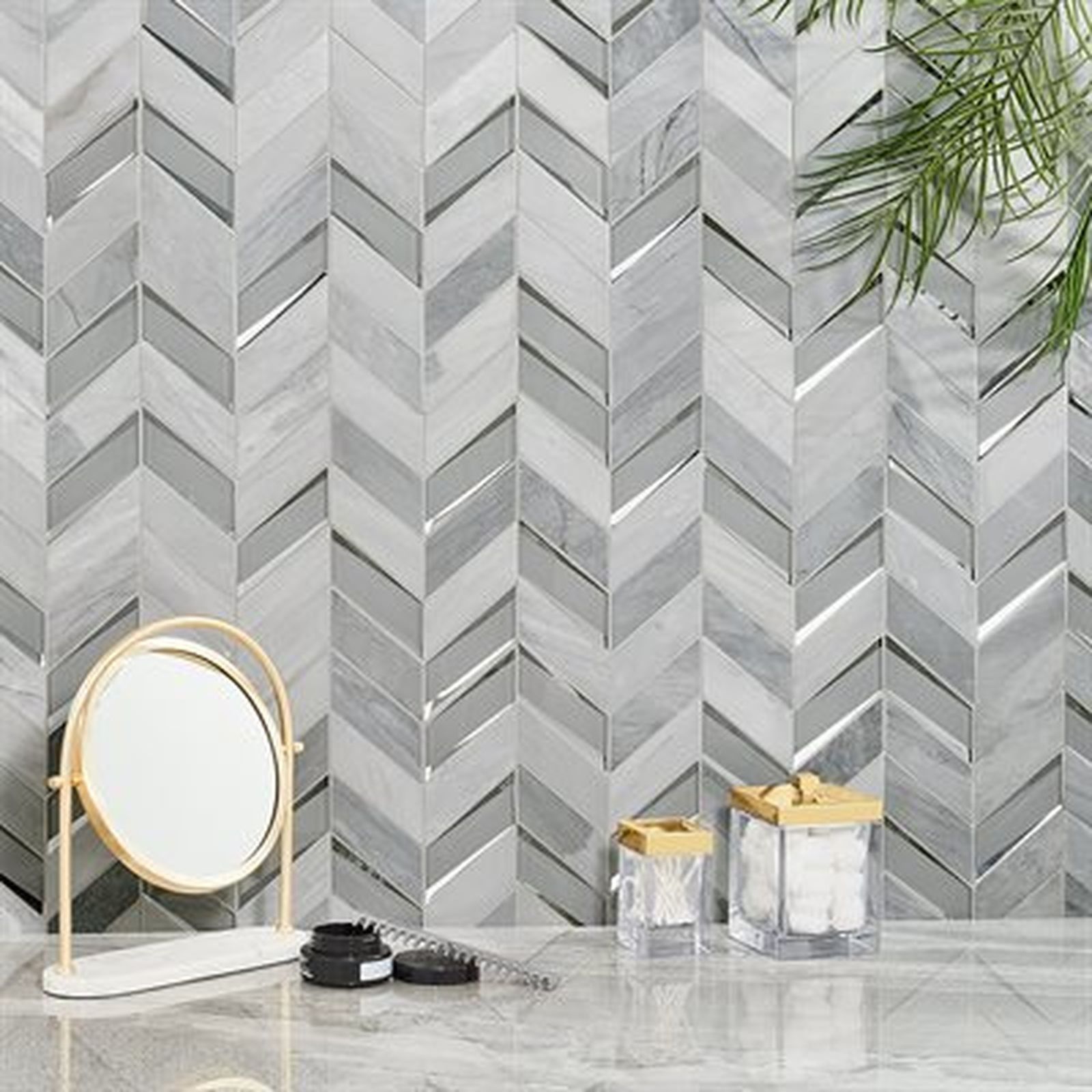 Chevron tile wall with mirror, containers, and greenery on a countertop.